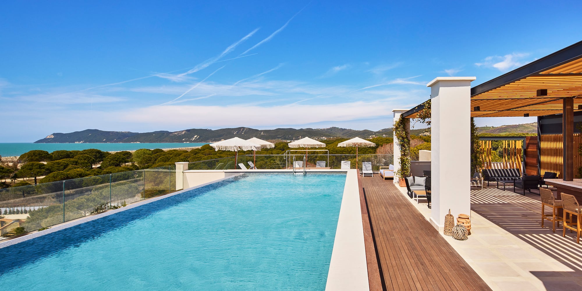 a swimming pool with a deck and a building with trees in the background