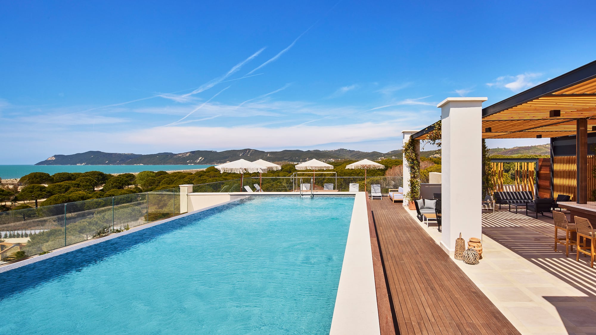 a swimming pool with a deck and a building with trees in the background