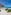 White sand beach, large palapa with bench, turquoise ocean, and blue sky.