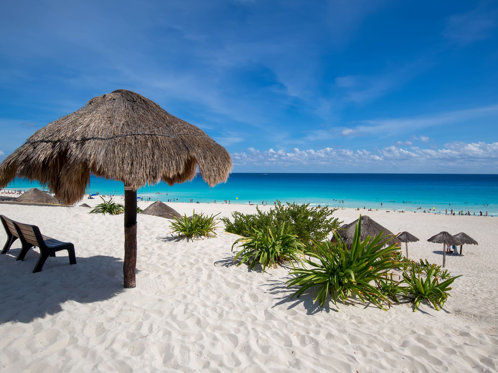 a beach with a straw umbrella and a chair