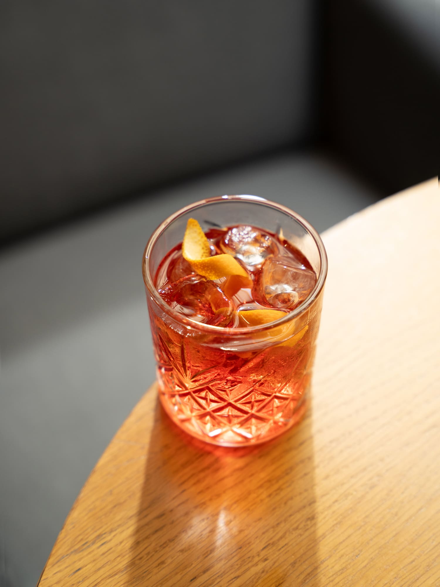 a glass with a drink and ice on a table