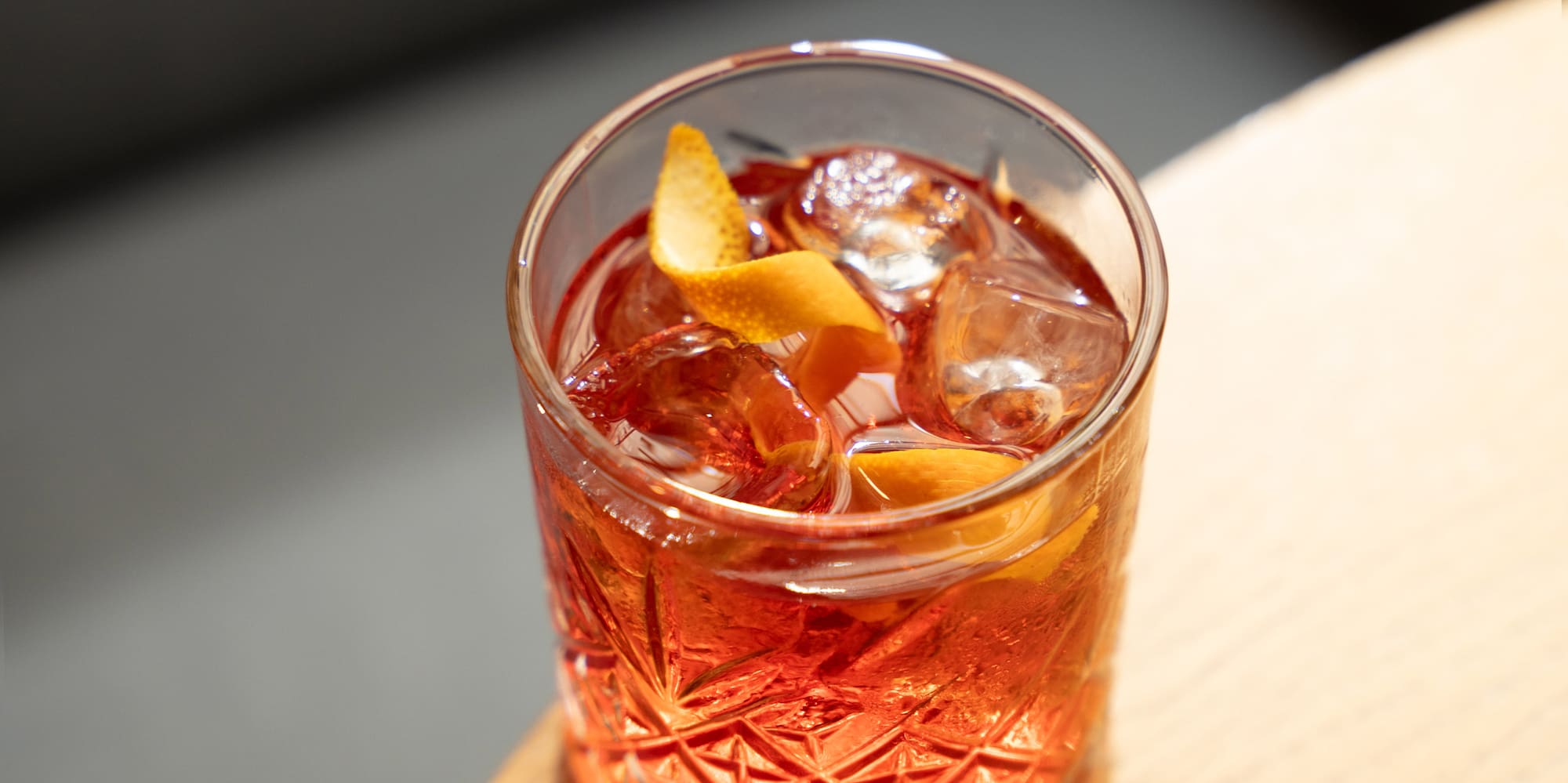 a glass with a drink and ice on a table