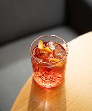 a glass with a drink and ice on a table