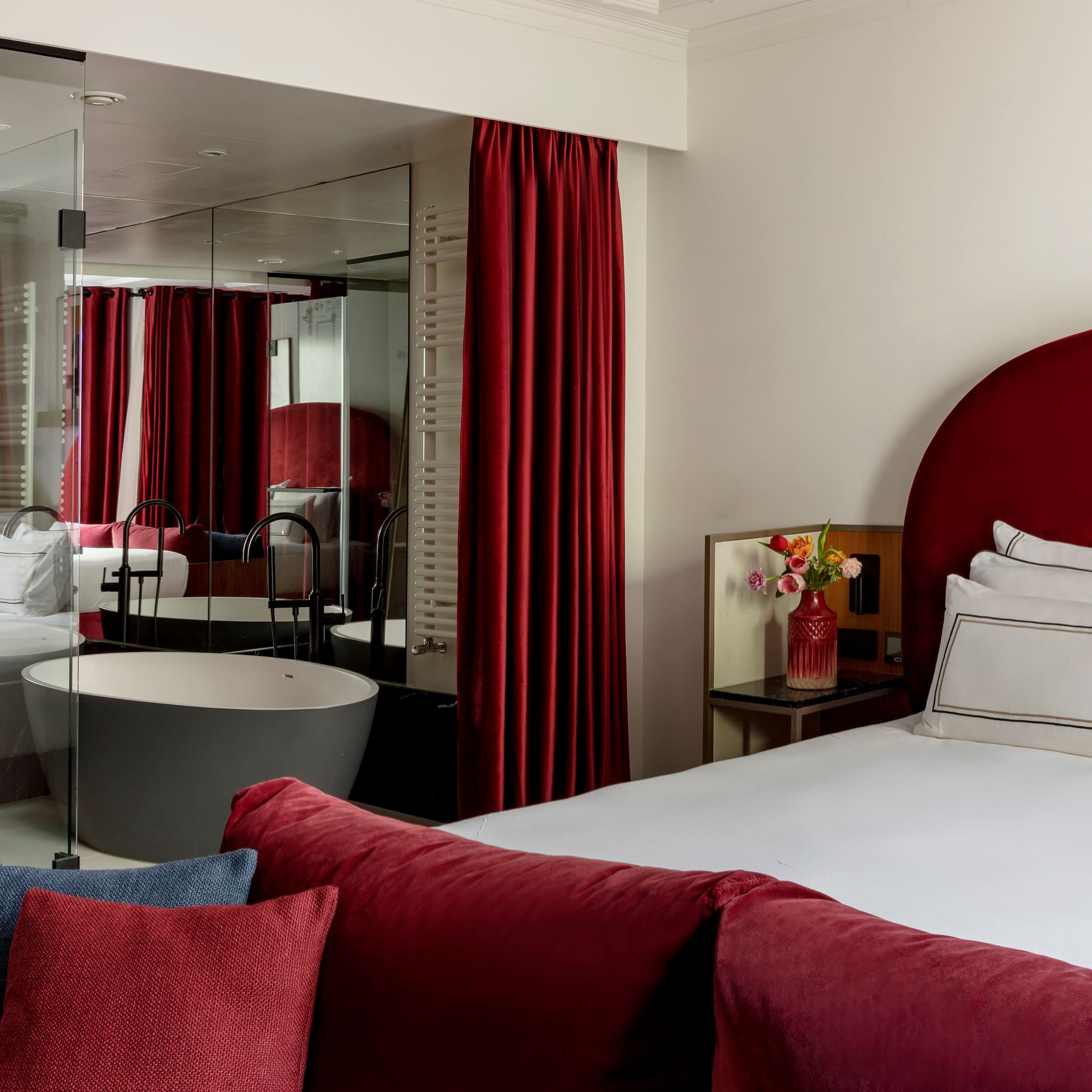 a bedroom with red curtains and a tub