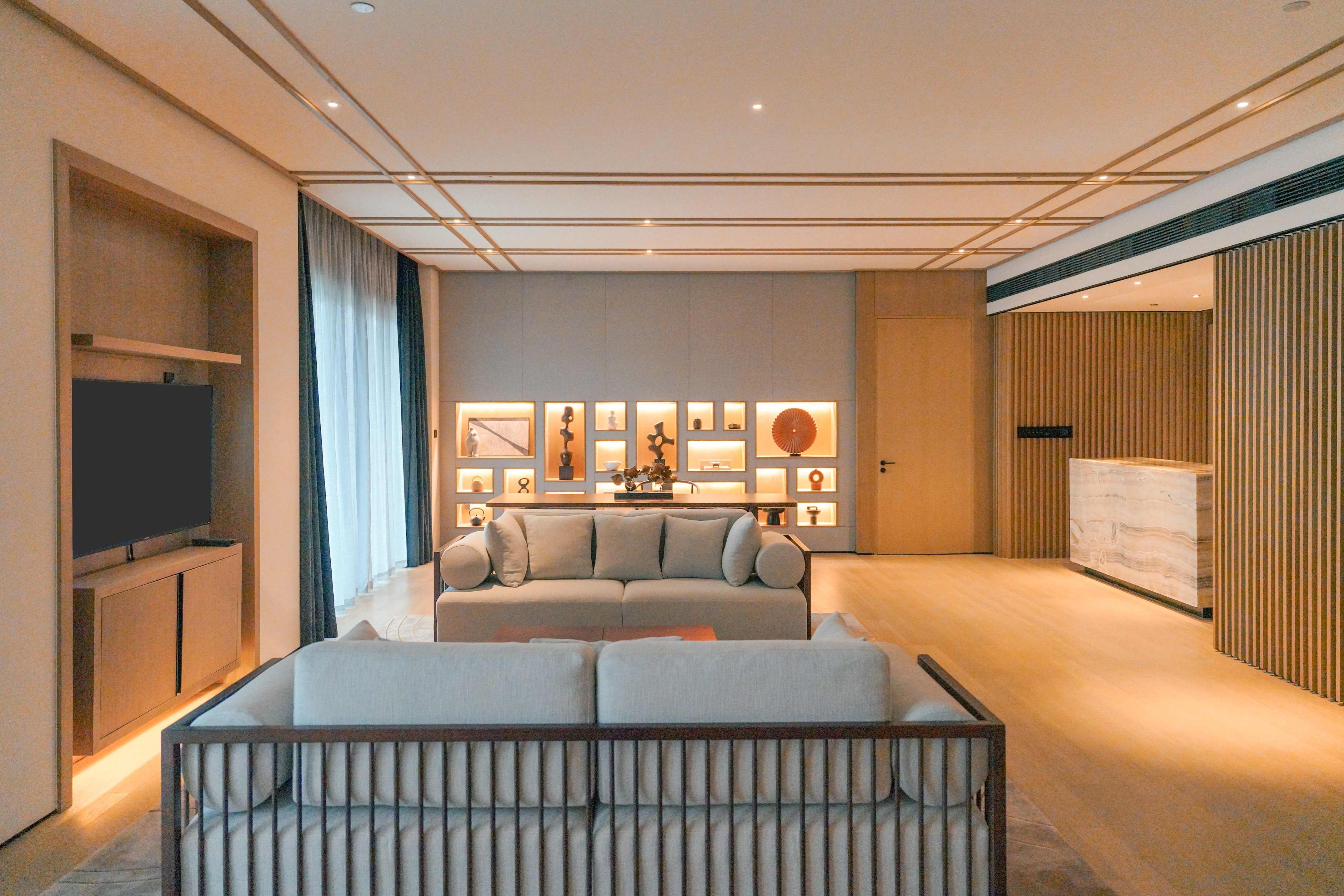 Elegant living room with light sofas, wooden decor, and illuminated wall art displays.