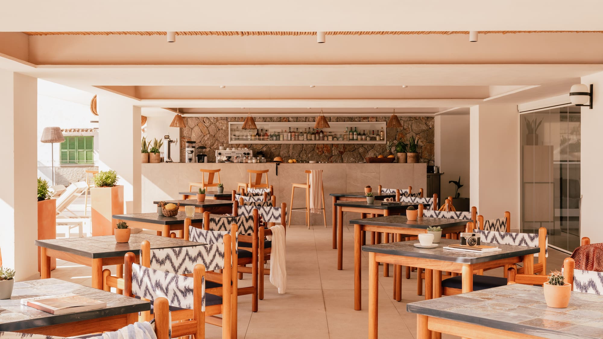 Bright resort restaurant and bar with wooden tables and patterned chairs.