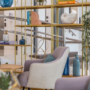a room with a gold shelf and chairs