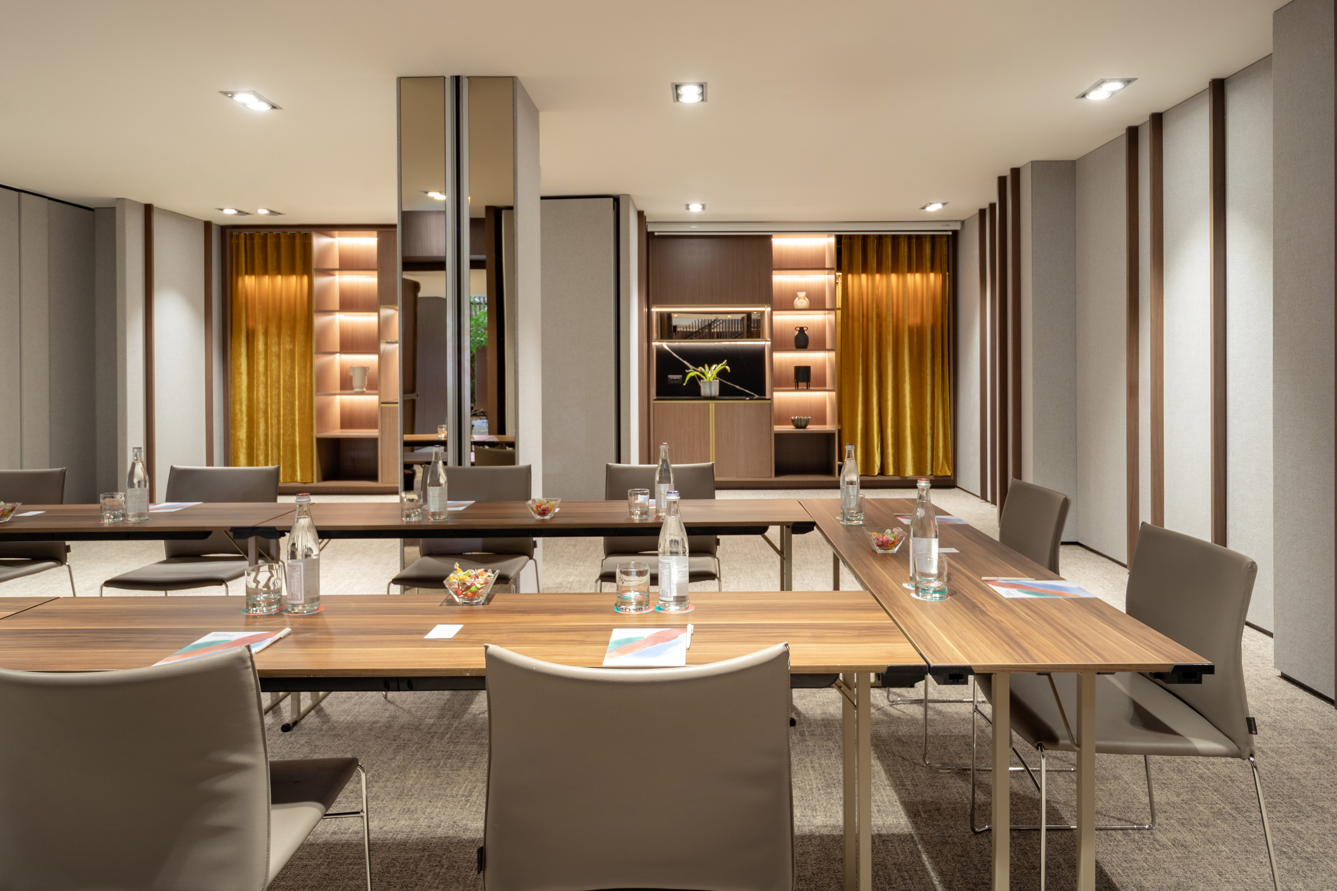 Modern conference room with U-shaped tables, chairs, and elegant warm lighting.