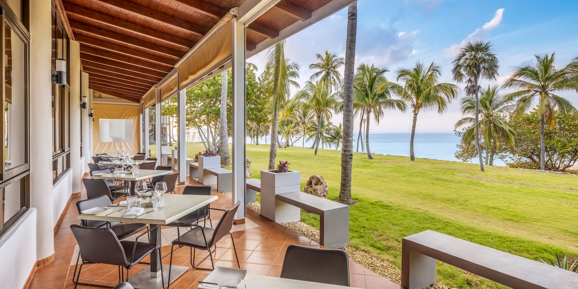 a restaurant with tables and chairs and grass and trees