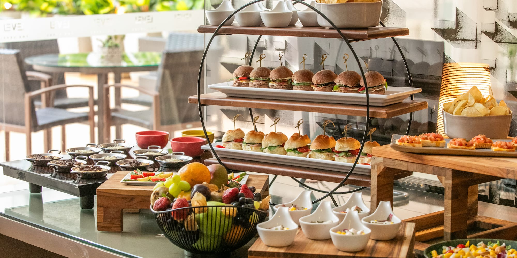 Restaurant buffet with mini burgers, fresh fruit, chips, and appetizers.