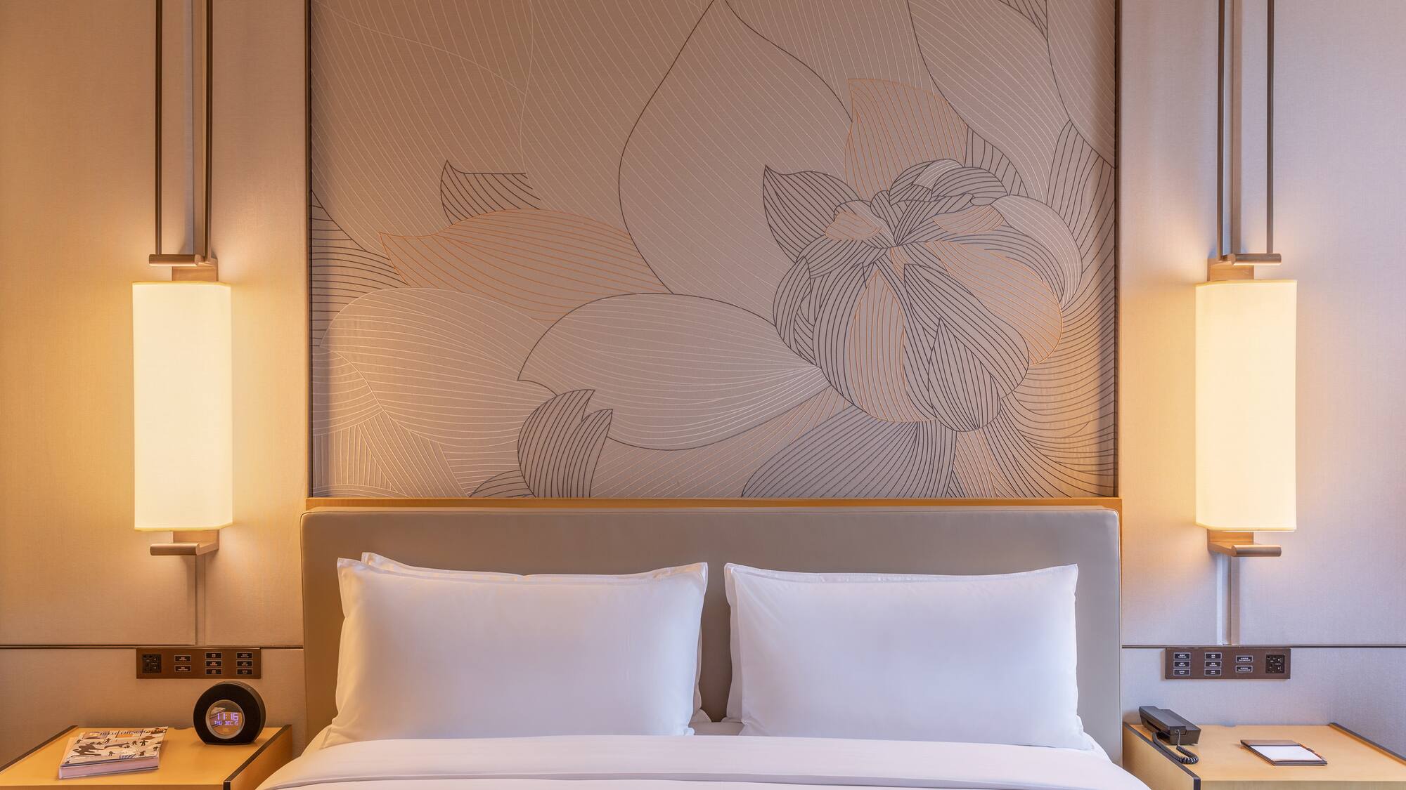 a bed with a wallpaper and lamps