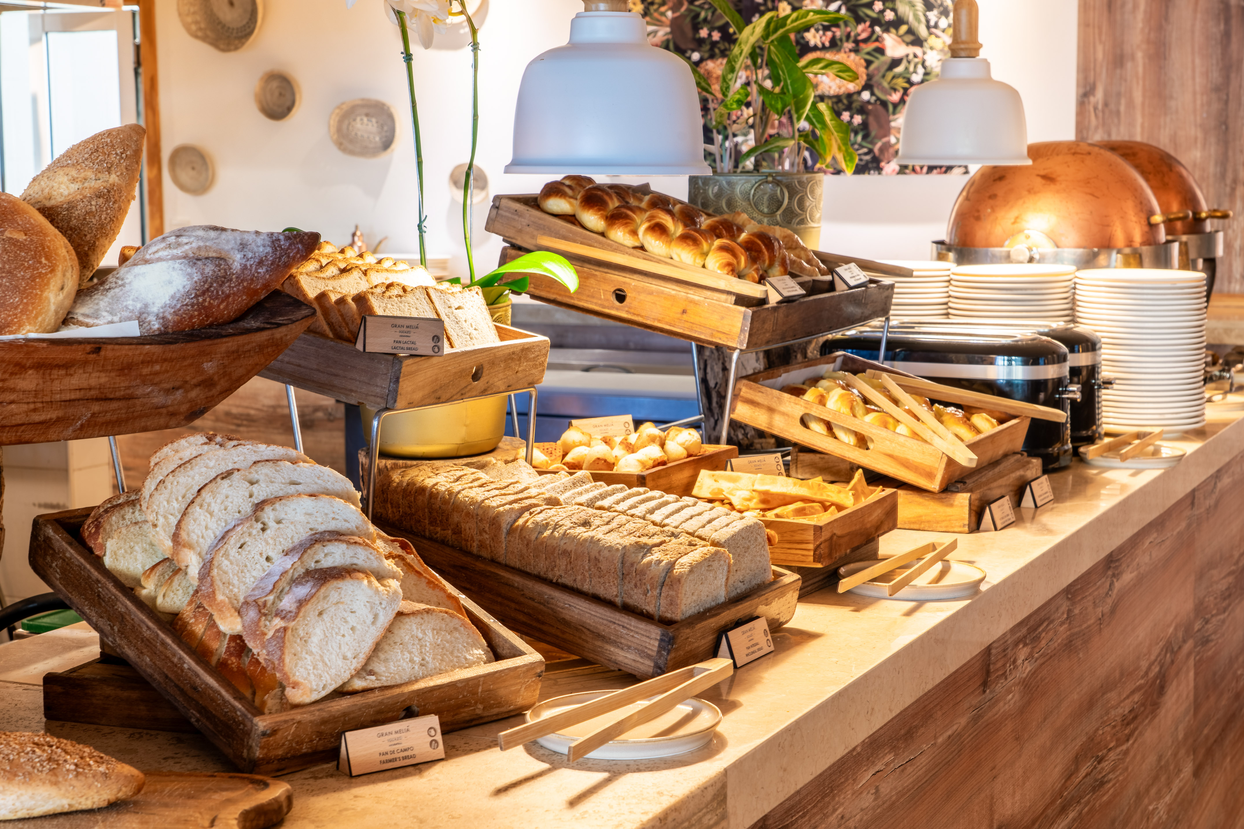 Breakfast buffet with diverse artisan breads, sliced loaves, and fresh croissants.