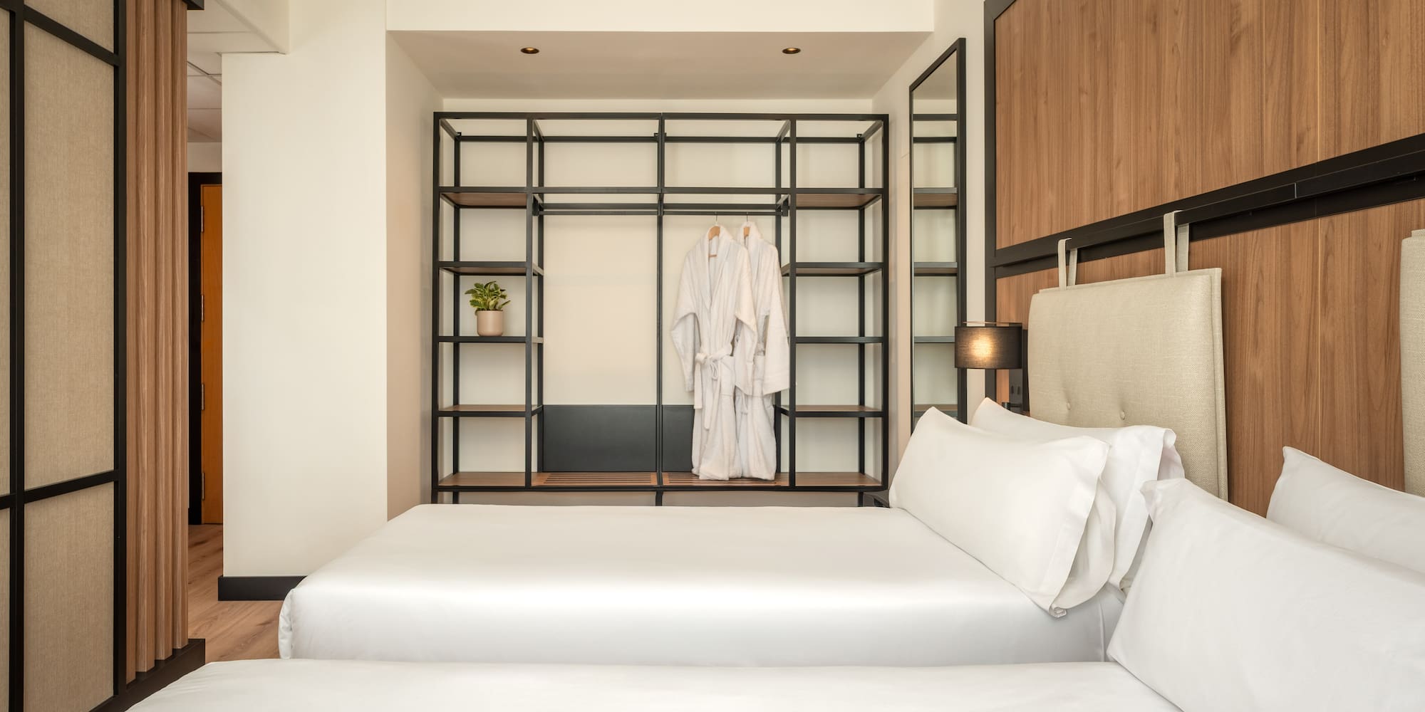 a room with two beds and a shelf with white towels
