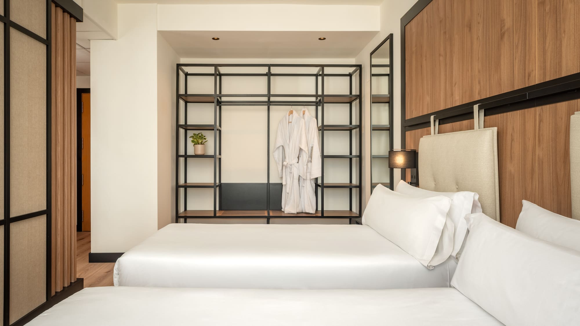 a room with two beds and a shelf with white towels