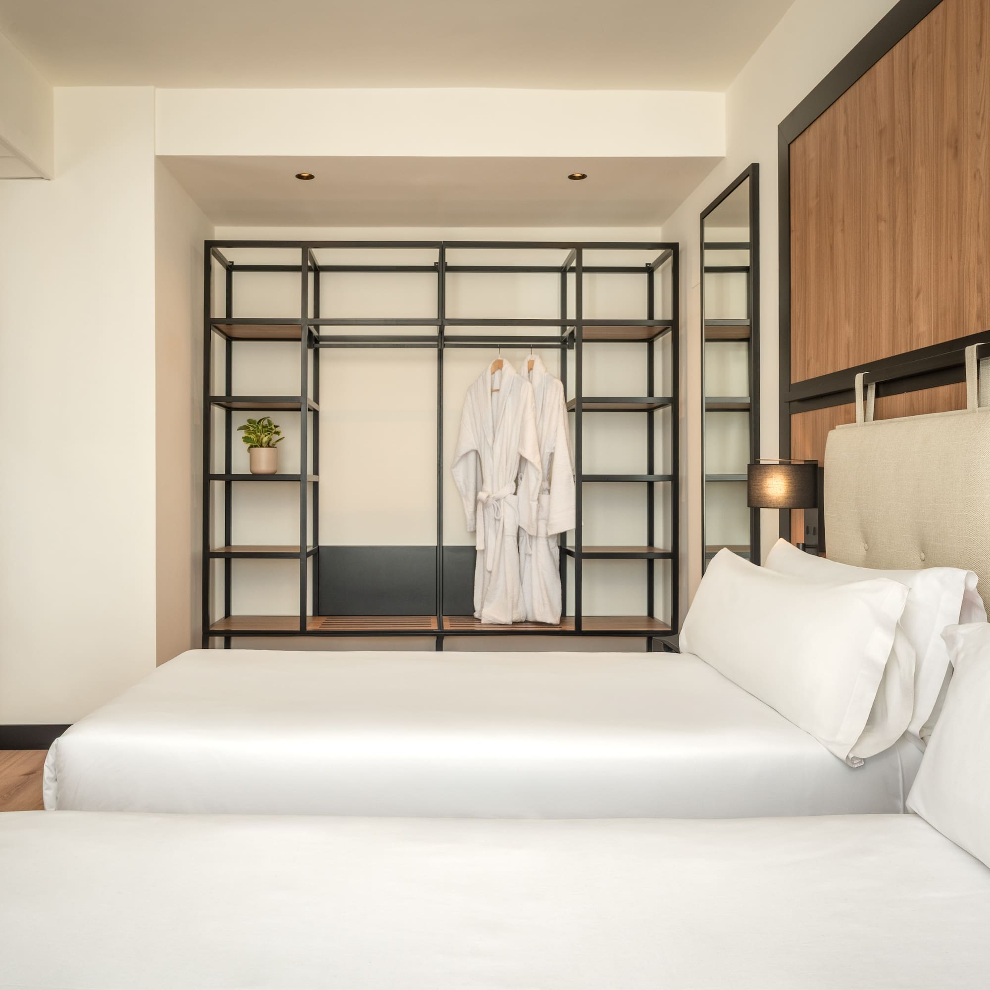 a room with two beds and a shelf with white towels