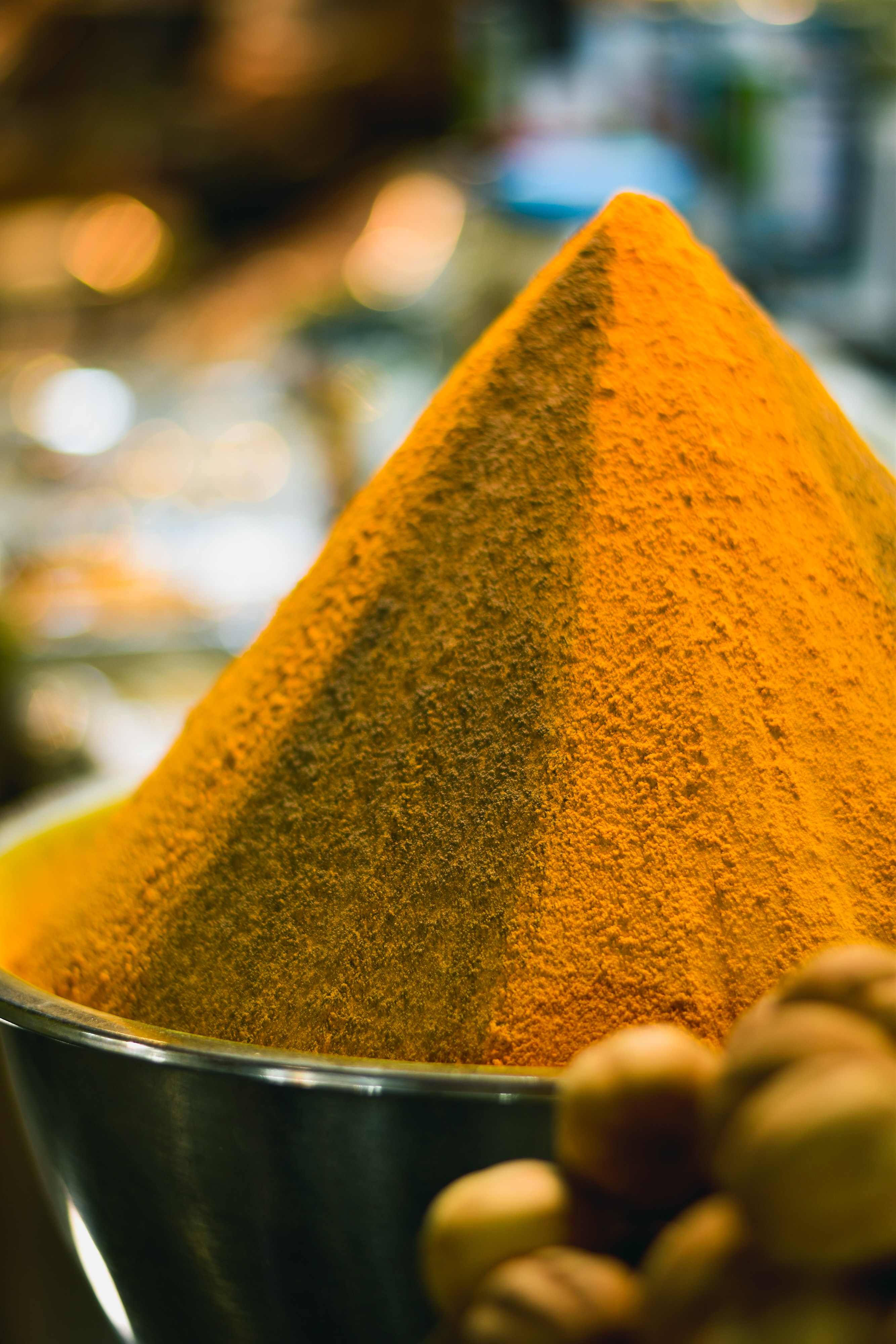 Mound of bright orange turmeric powder in a market bin.