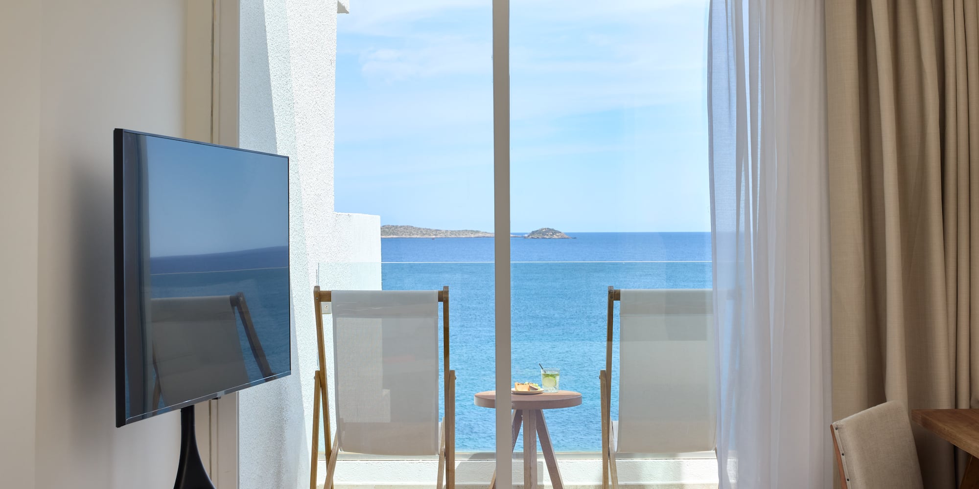 a room with a television and a view of the ocean