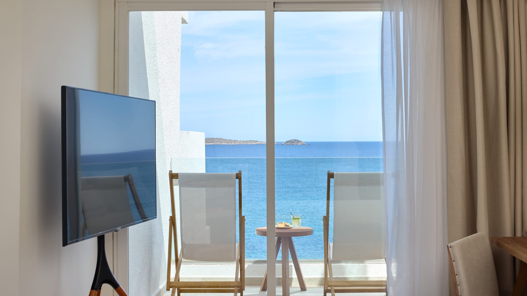 a room with a television and a view of the ocean