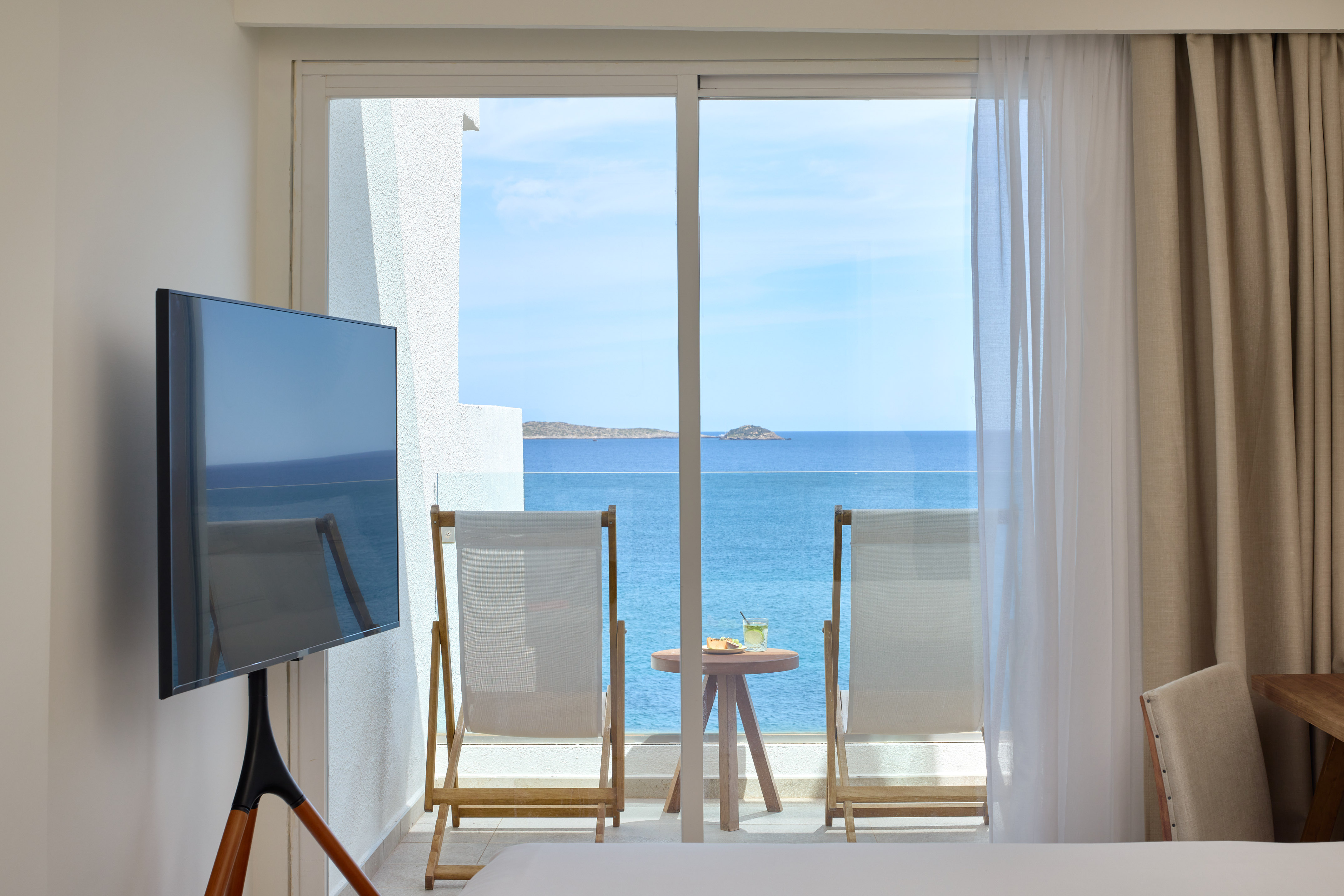 a room with a television and a view of the ocean