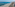 White umbrellas line a sandy beach with blue ocean and a coastal boardwalk.
