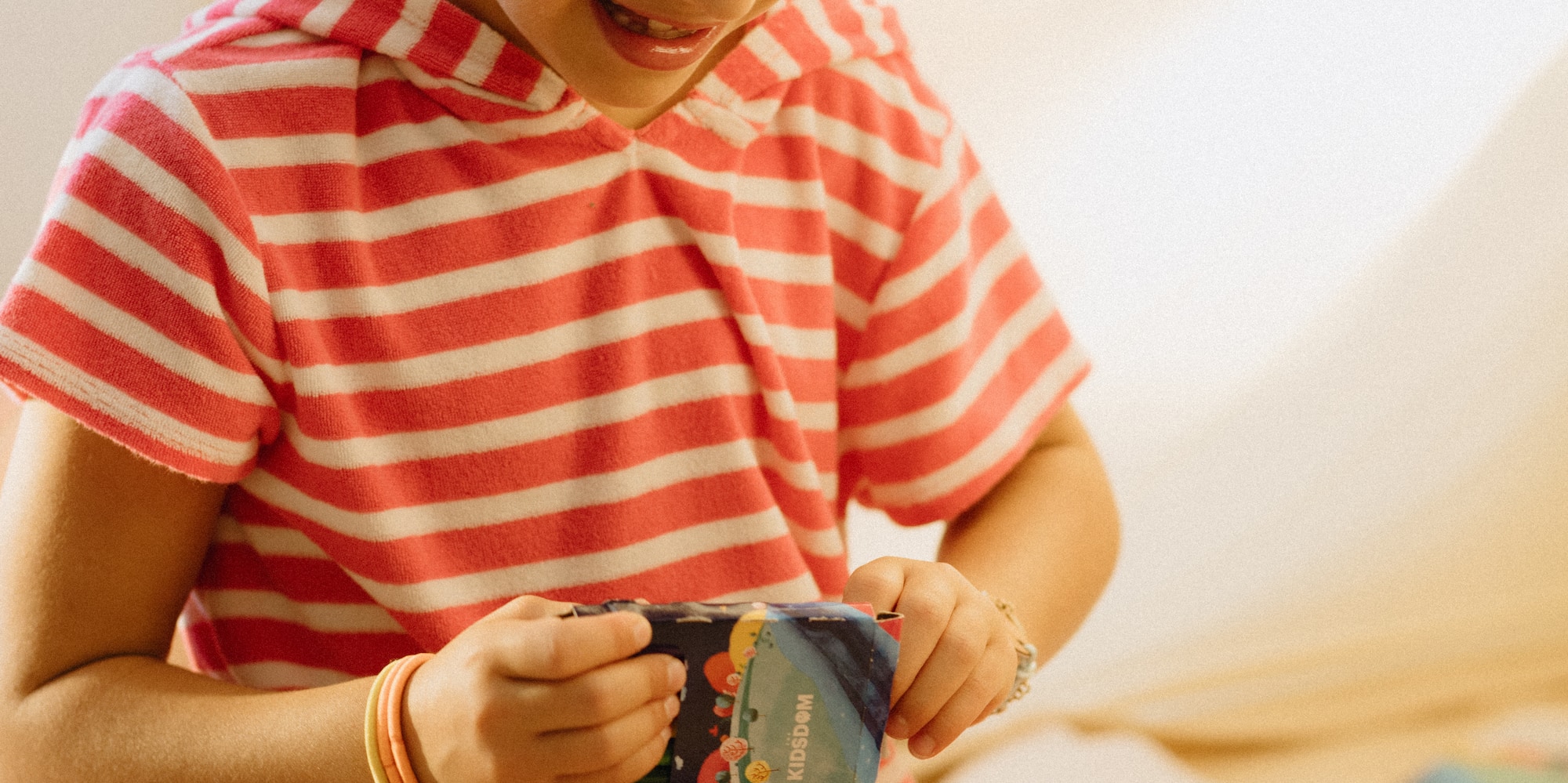 Girl in striped outfit happily playing with a KIDSDOM art kit.