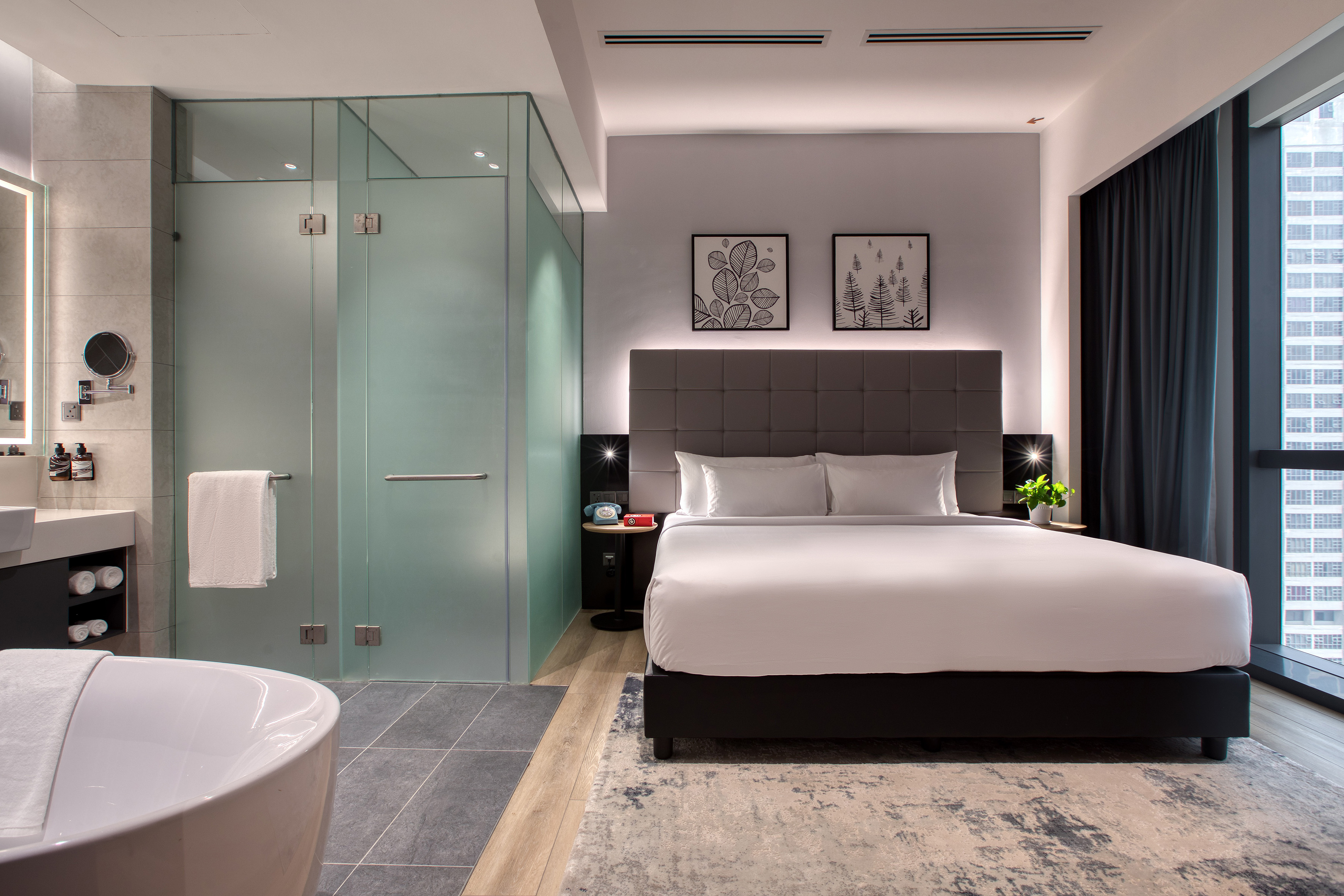 Contemporary hotel suite with king bed, luxury bathroom, and city view.