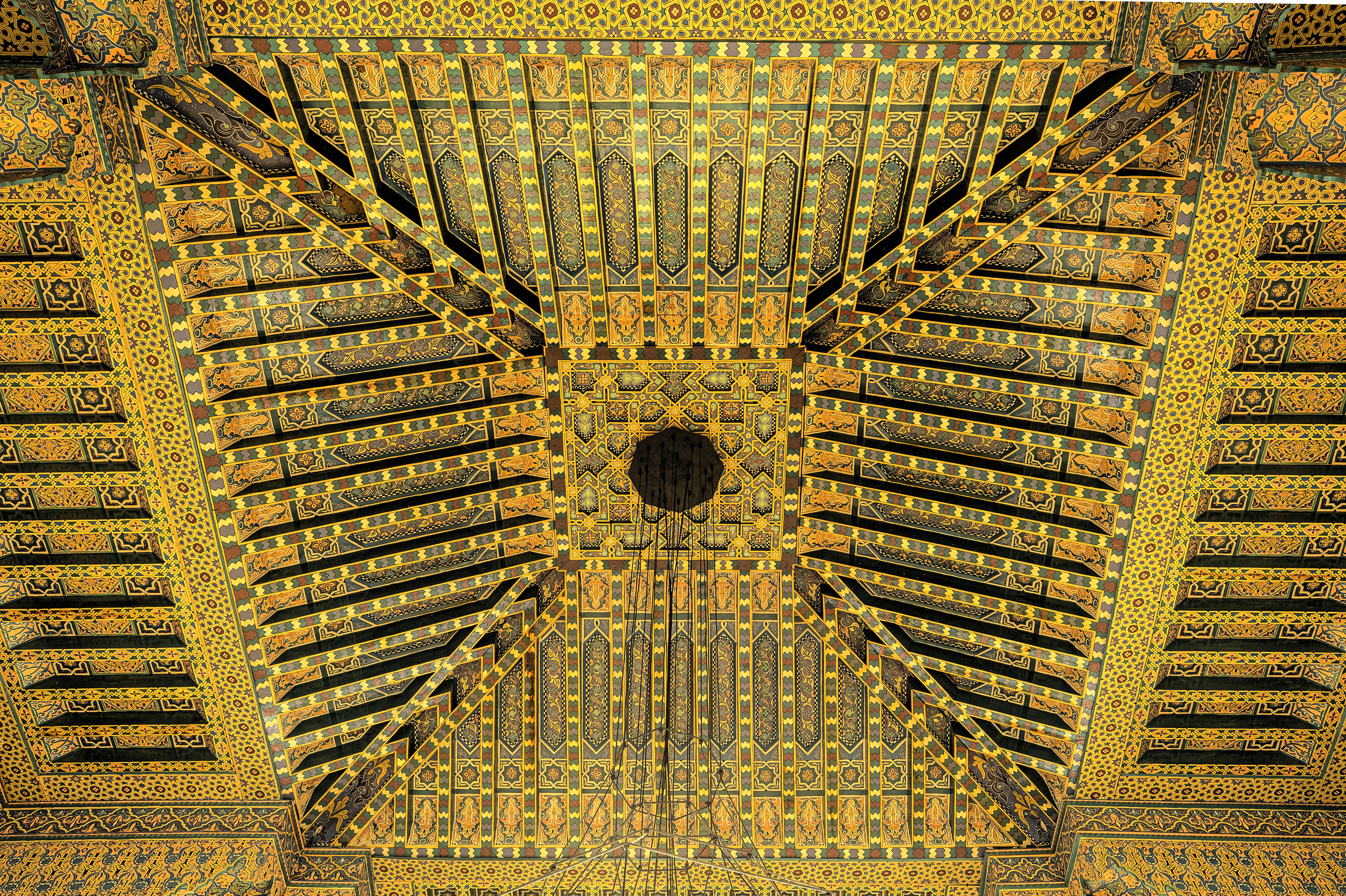 Moroccan carved ceiling with intricate gold and green geometric patterns.
