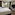 Habitación de hotel moderna con cama, TV y gran ventanal urbano.