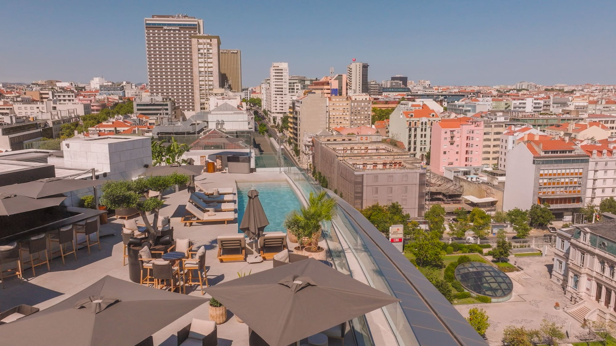 a rooftop view of a city with a pool and umbrellas
