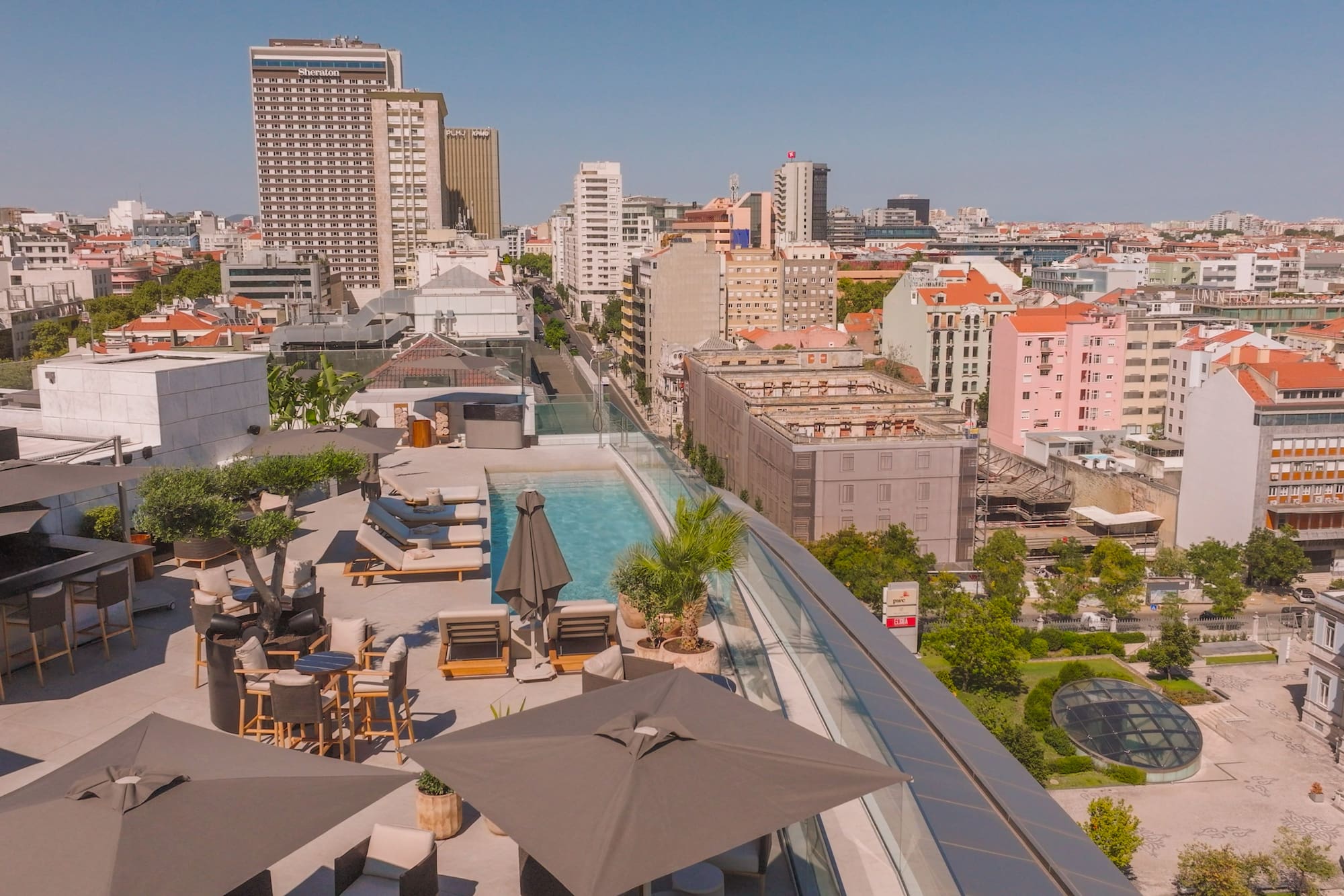 a rooftop view of a city with a pool and umbrellas