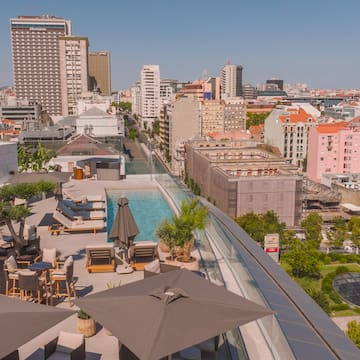 a rooftop view of a city with a pool and umbrellas