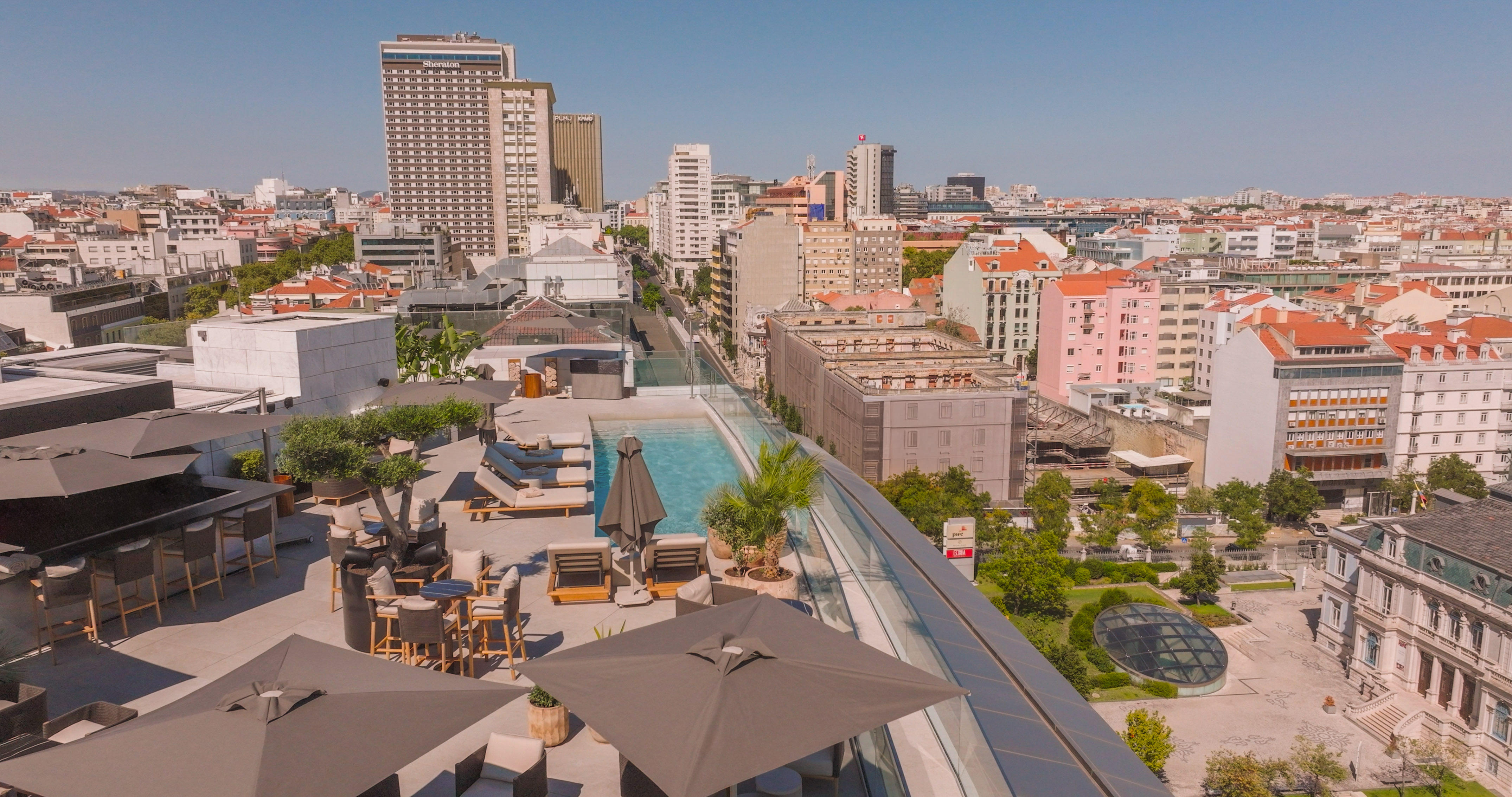 a rooftop view of a city with a pool and umbrellas