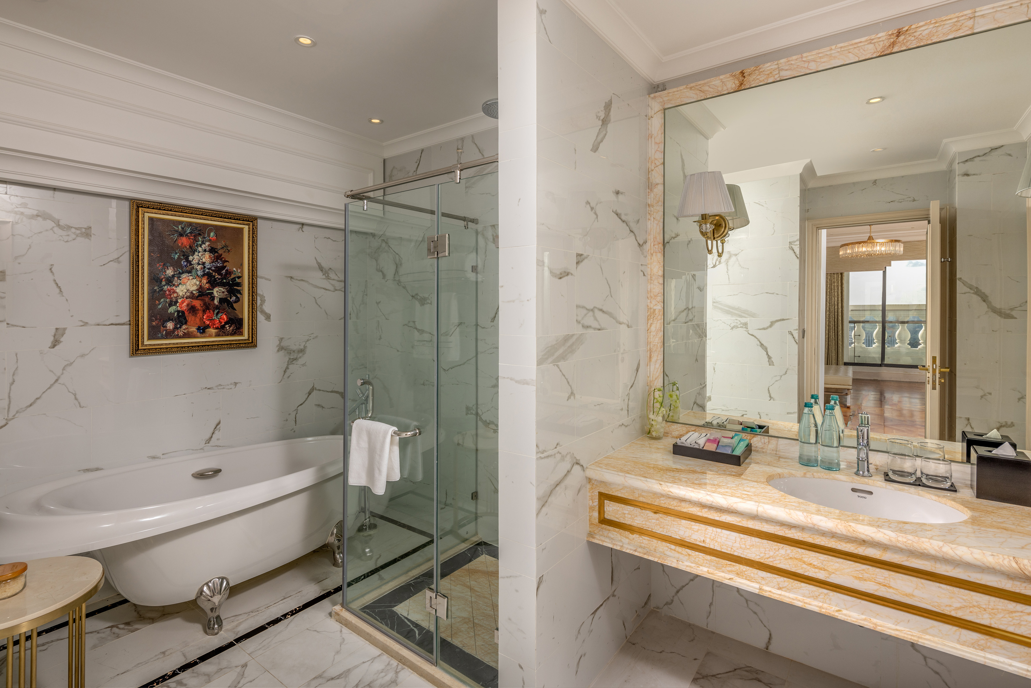 Elegant hotel bathroom with marble, freestanding tub, glass shower, and vanity.