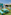 Área de juegos KidsDom exterior con mesas turquesa, peluches y césped.