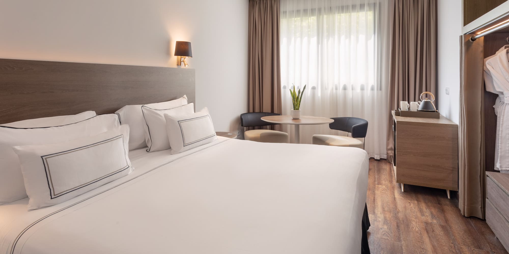 Comfortable hotel room with white king bed, cozy sitting area, and wood floors.