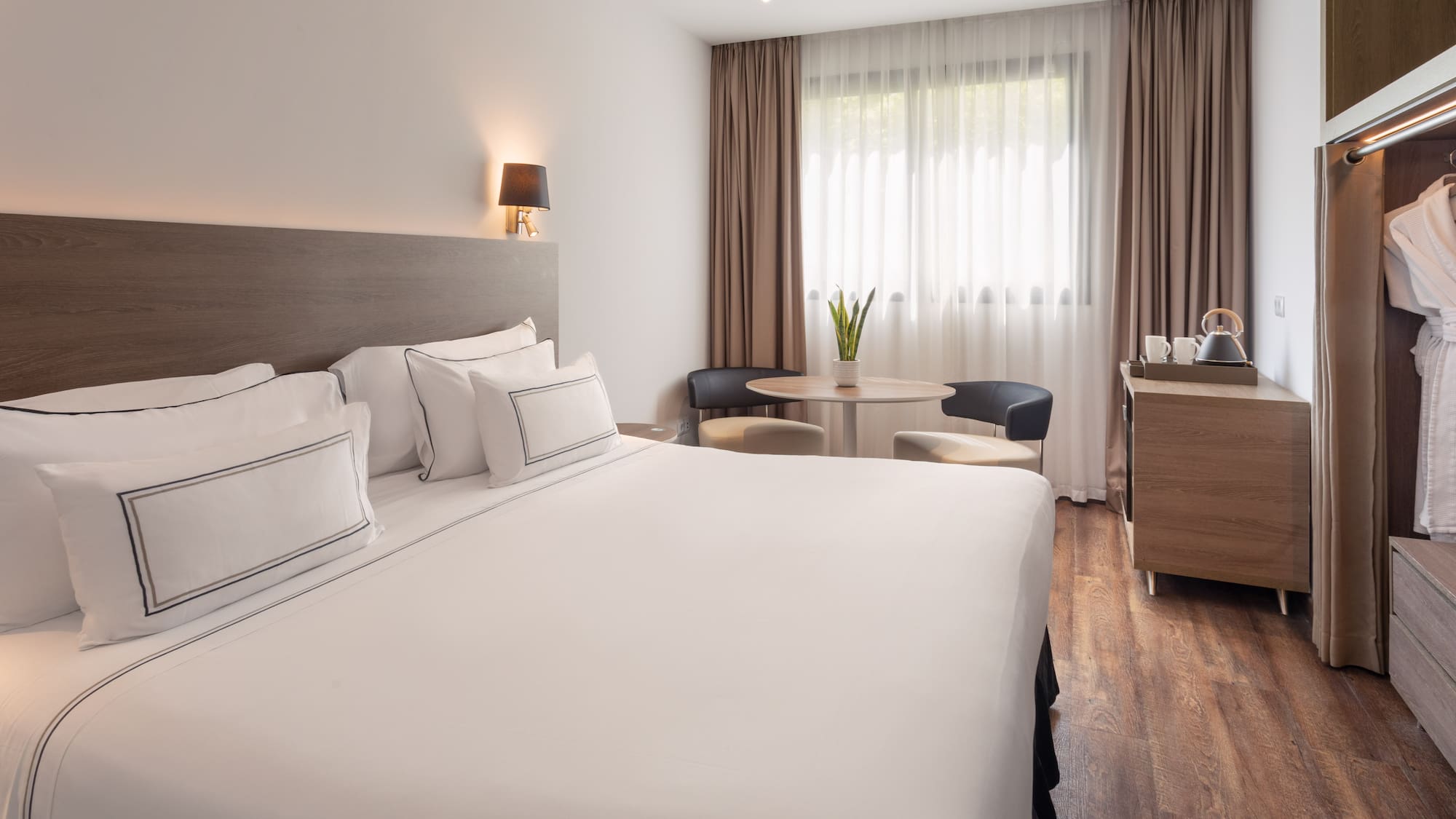 Comfortable hotel room with white king bed, cozy sitting area, and wood floors.