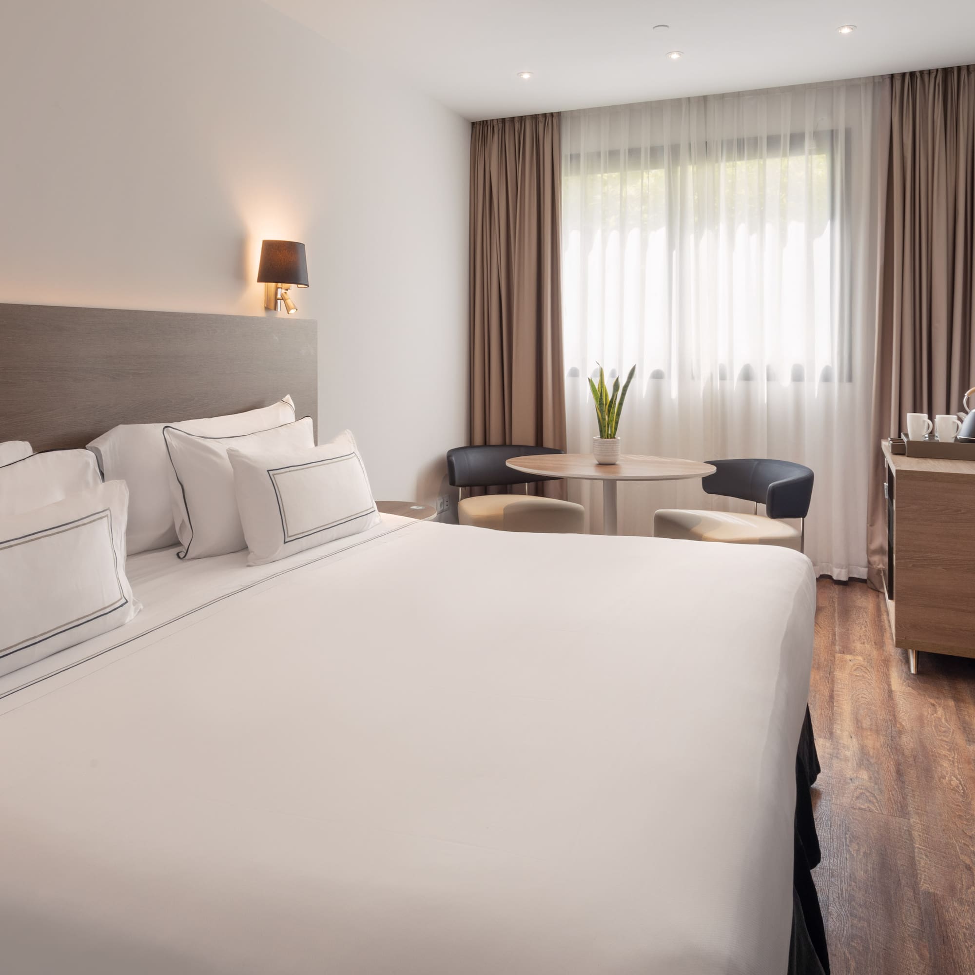 Comfortable hotel room with white king bed, cozy sitting area, and wood floors.