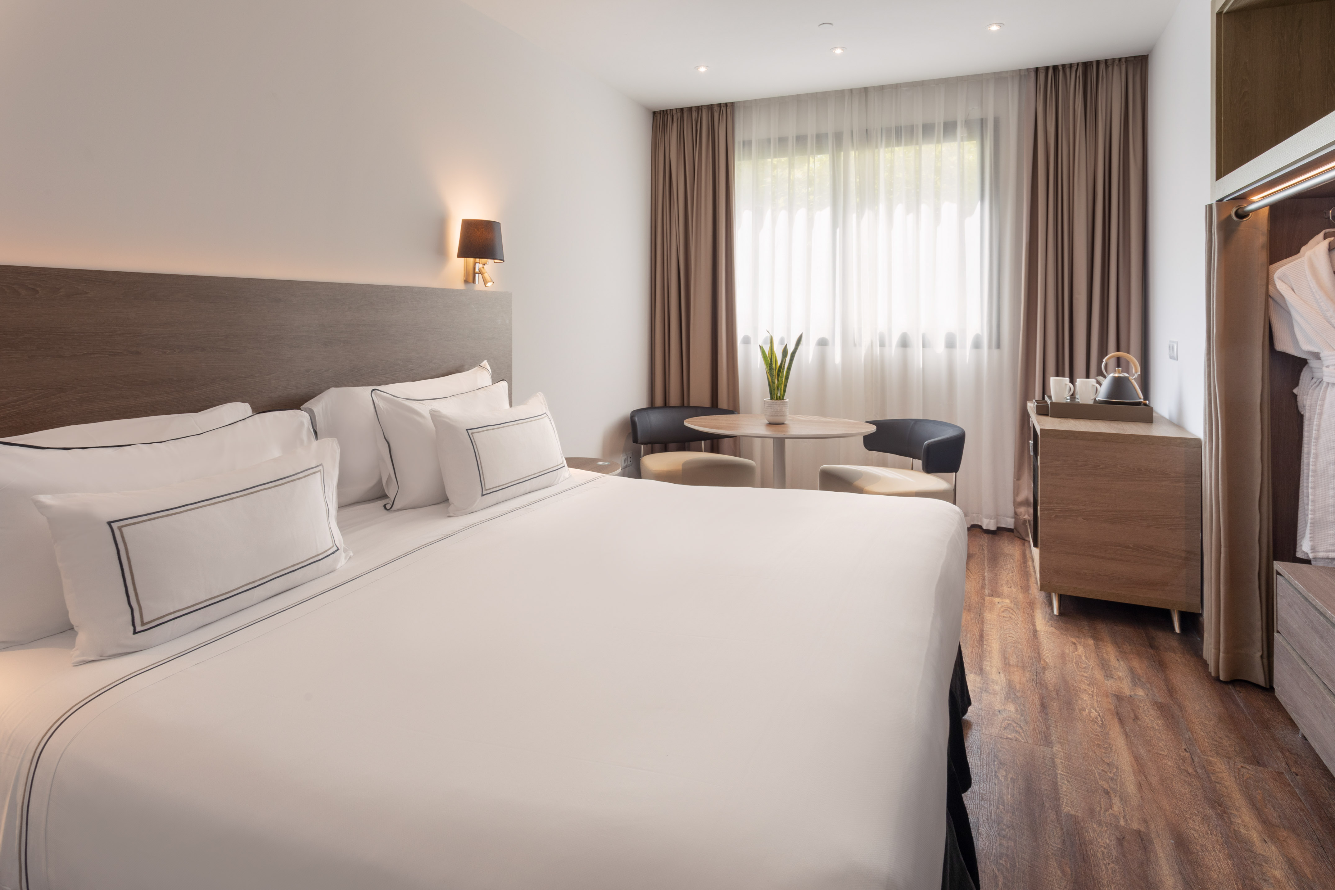 Comfortable hotel room with white king bed, cozy sitting area, and wood floors.