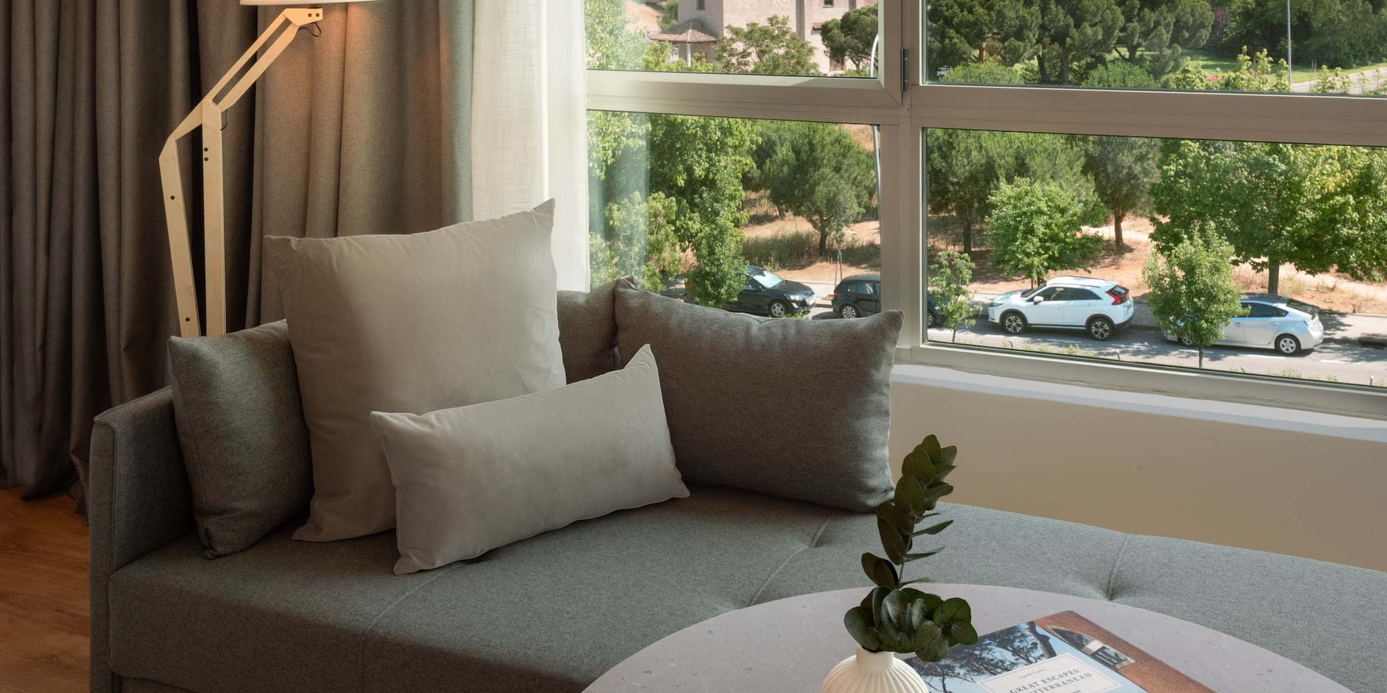 a couch with pillows and a vase on a table with a window