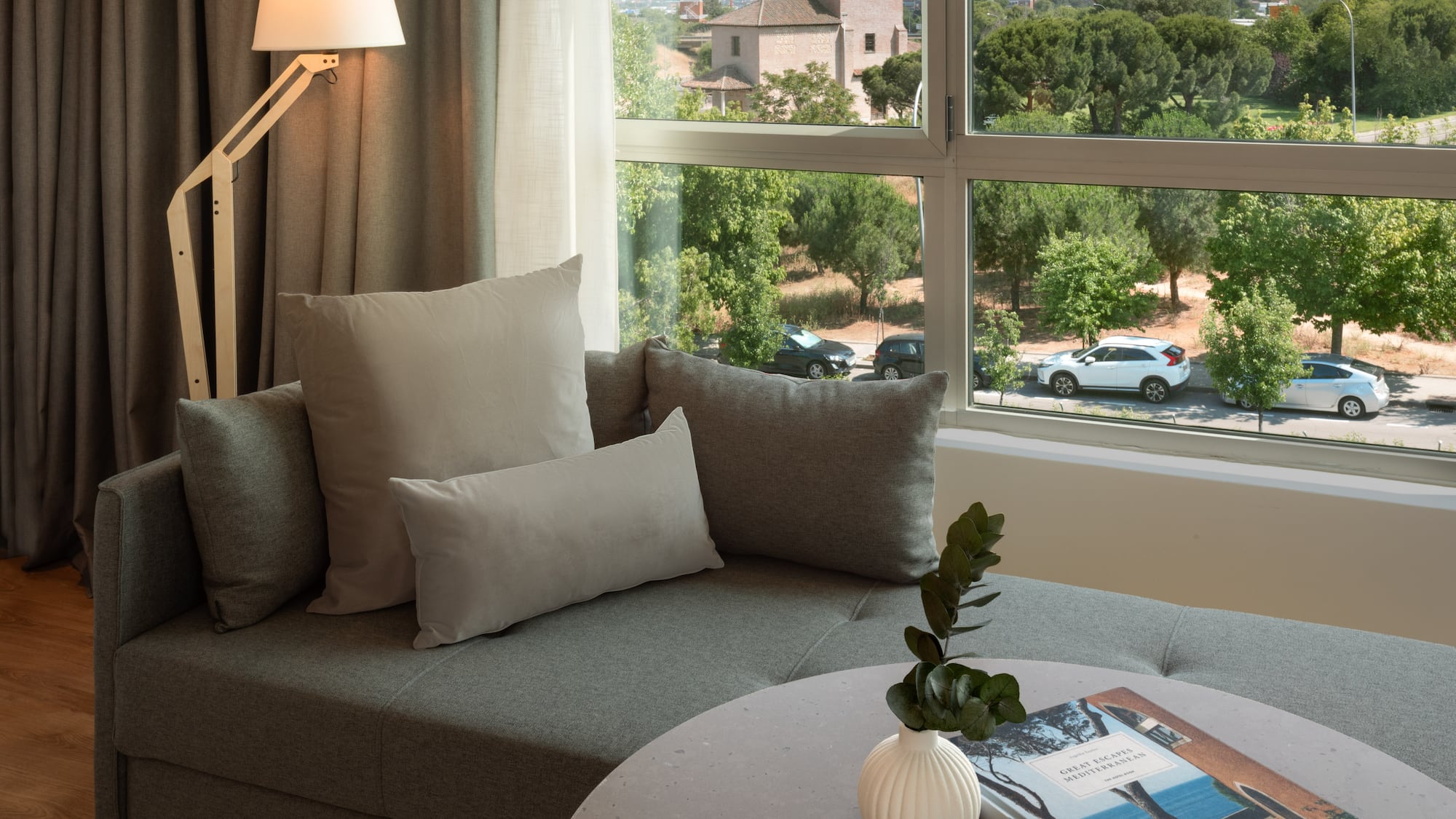 a couch with pillows and a vase on a table with a window