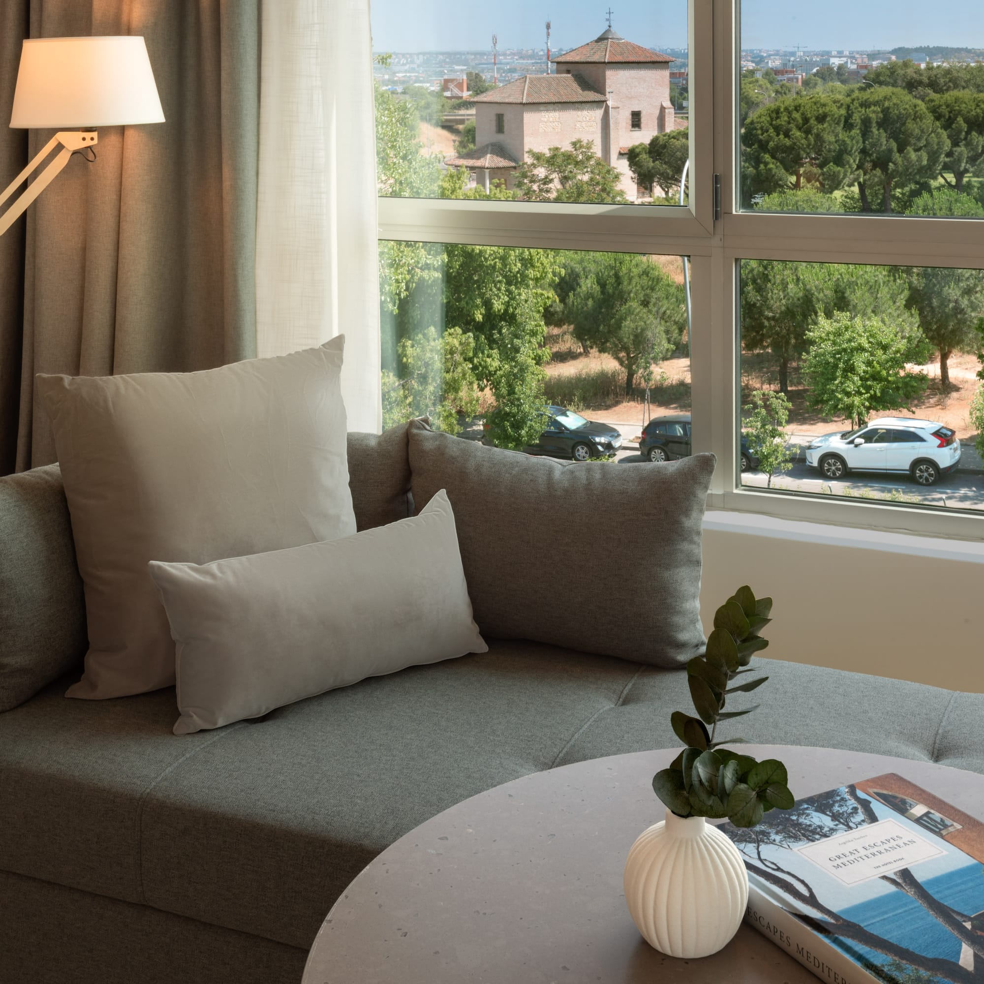 a couch with pillows and a vase on a table with a window