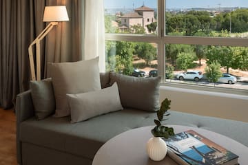 a couch with pillows and a vase on a table with a window