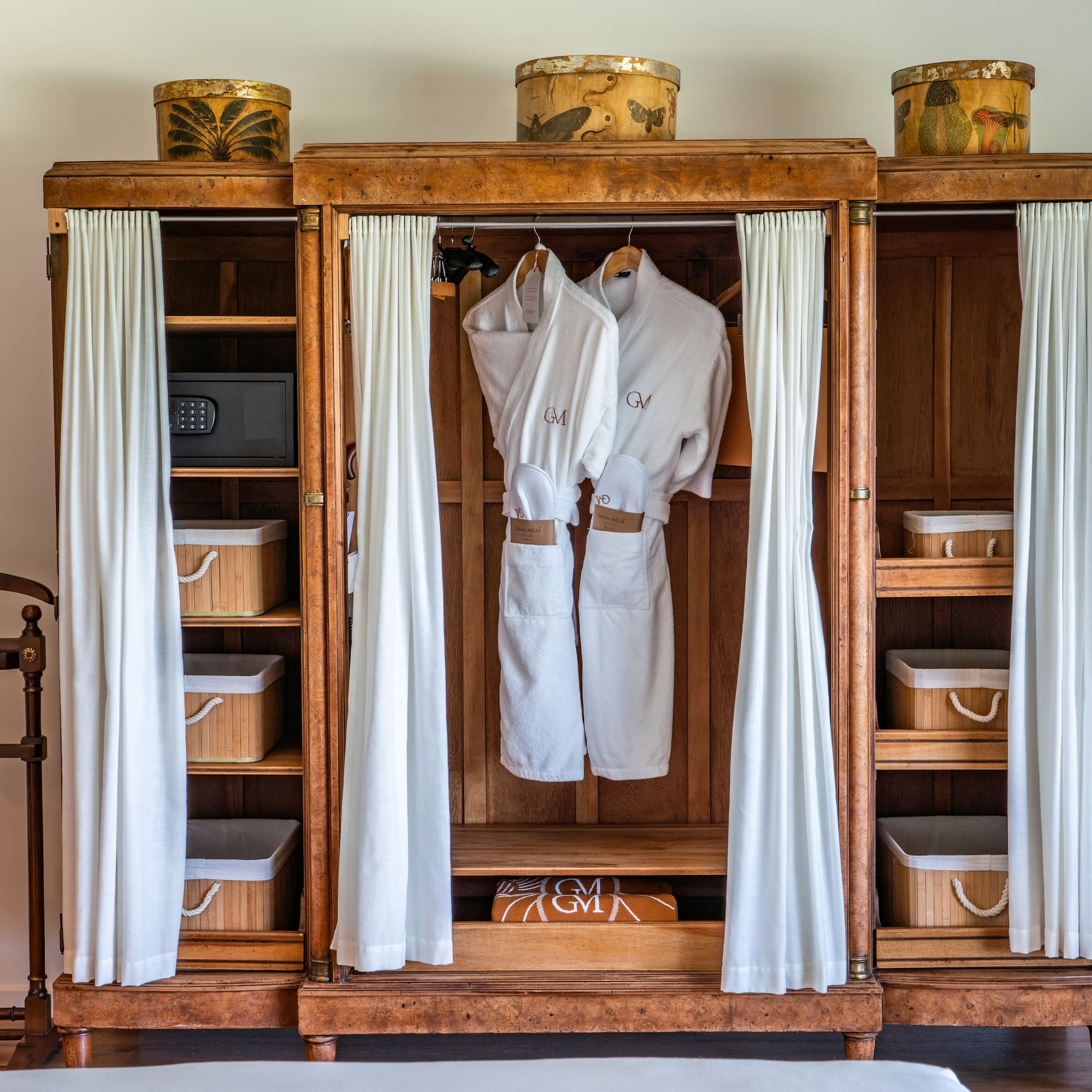 a wooden cabinet with white robes and baskets