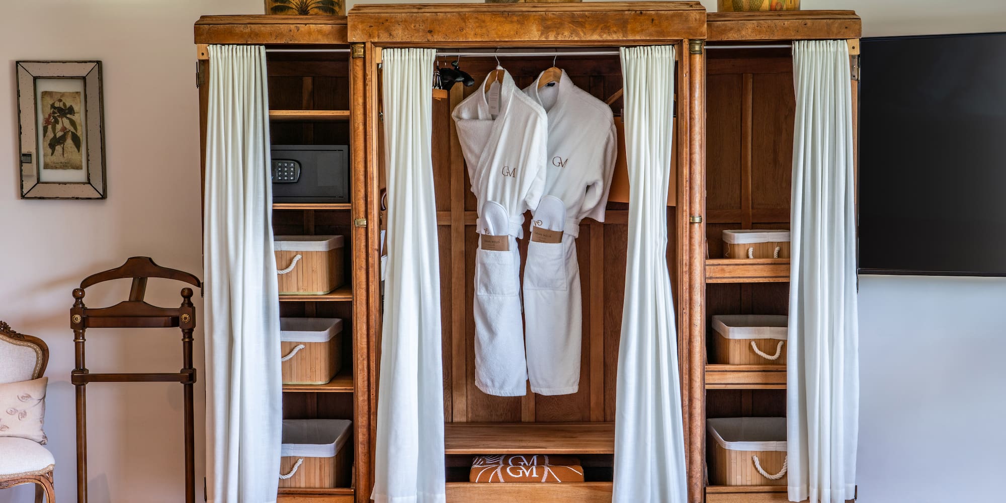 a wooden cabinet with white robes and baskets