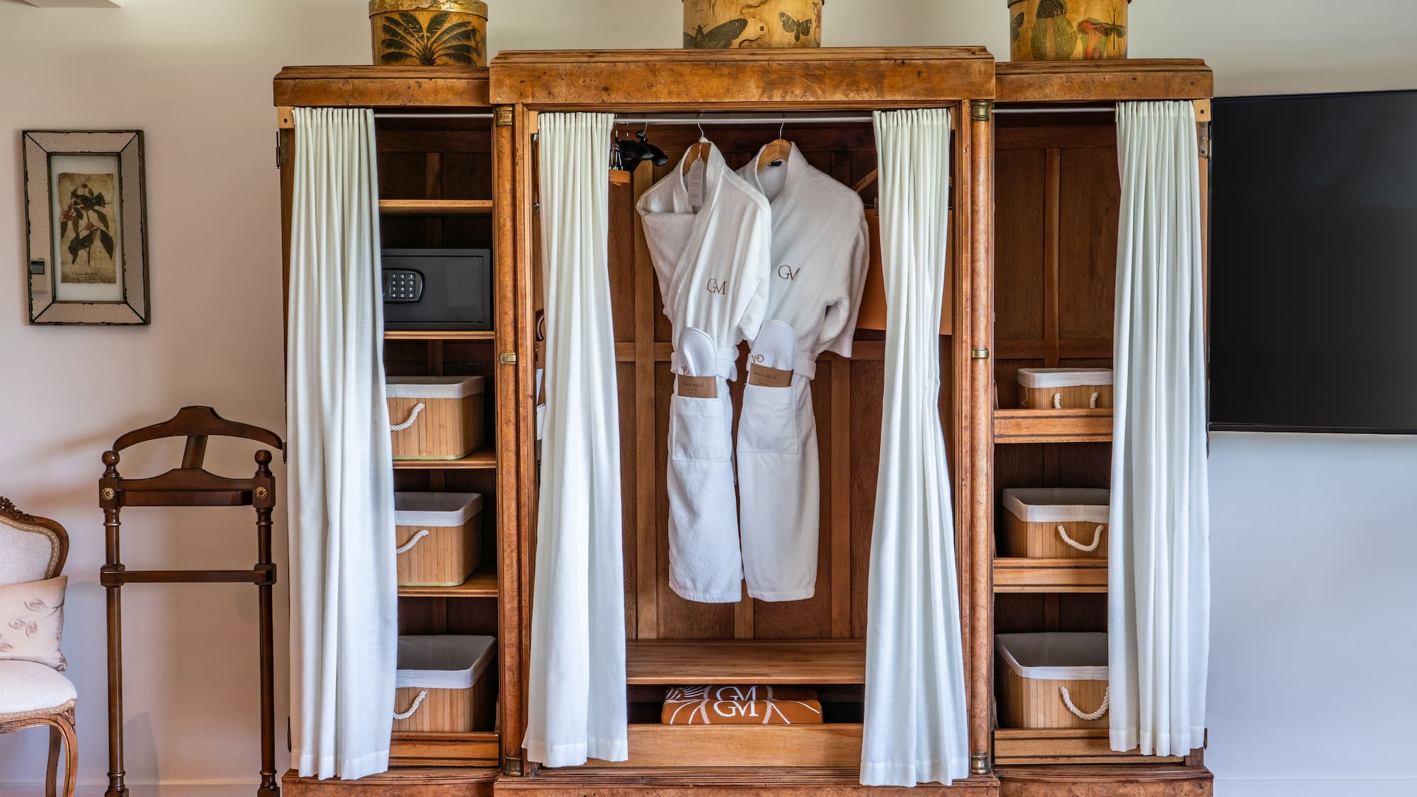 a wooden cabinet with white robes and baskets