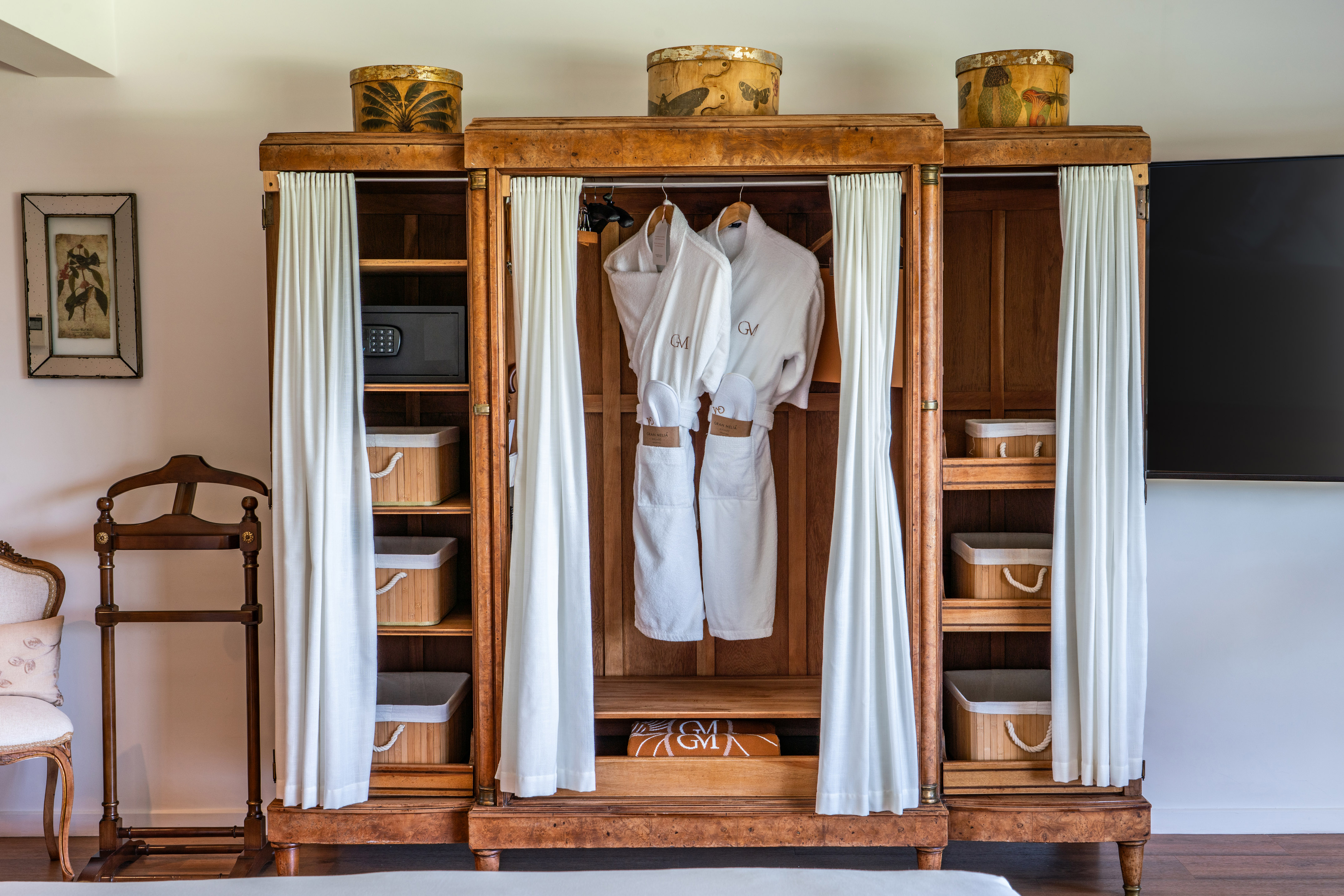a wooden cabinet with white robes and baskets