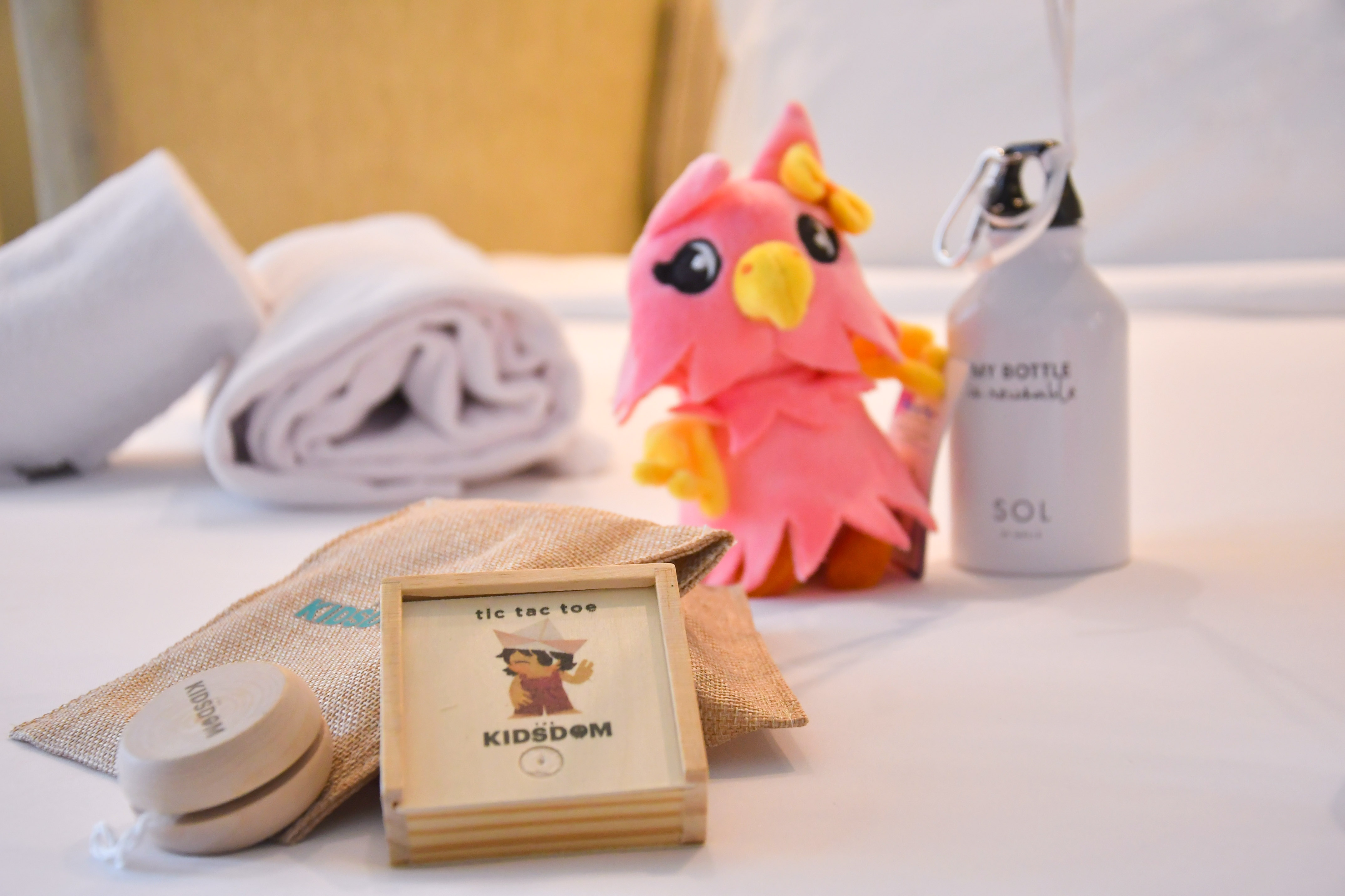 Hotel kids' kit: pink bird plush, tic-tac-toe, yoyo, reusable bottle.