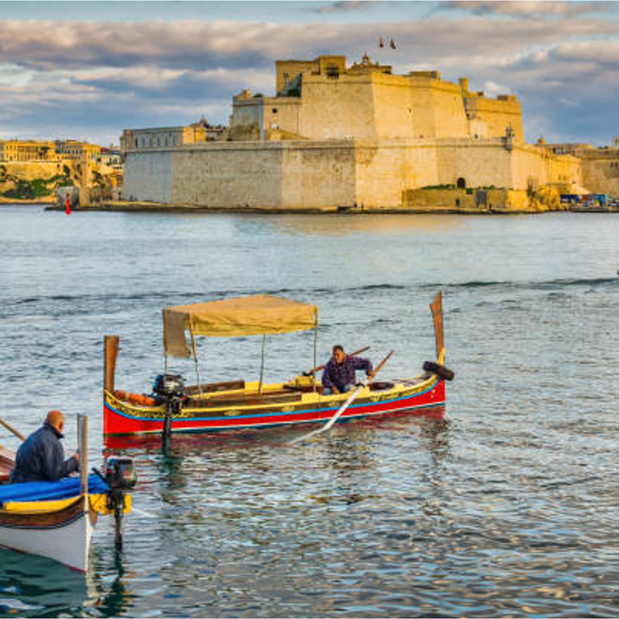 Colorful dgħajsas in Malta's Grand Harbour, Fort St. Angelo behind.