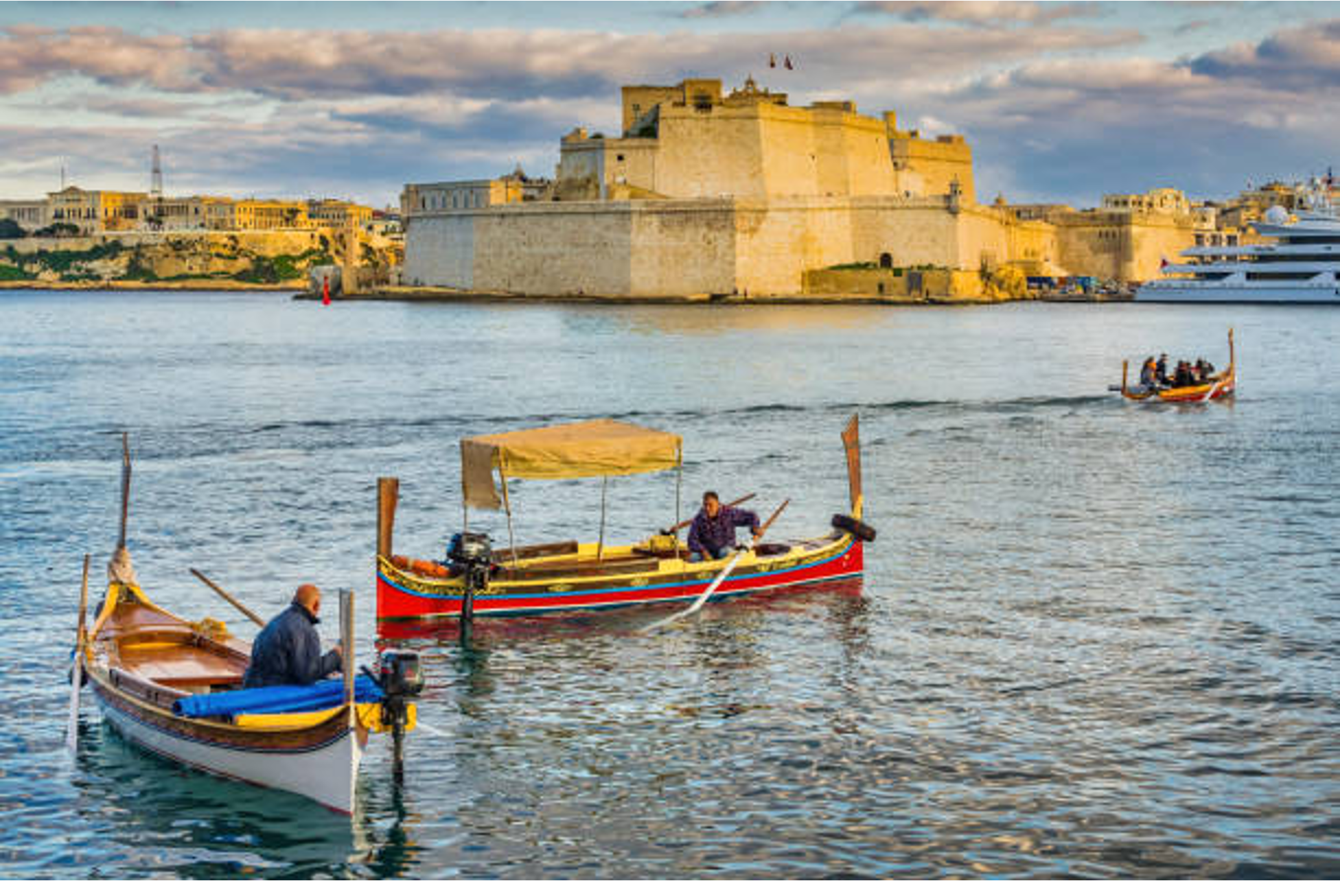 Colorful dgħajsas in Malta's Grand Harbour, Fort St. Angelo behind.