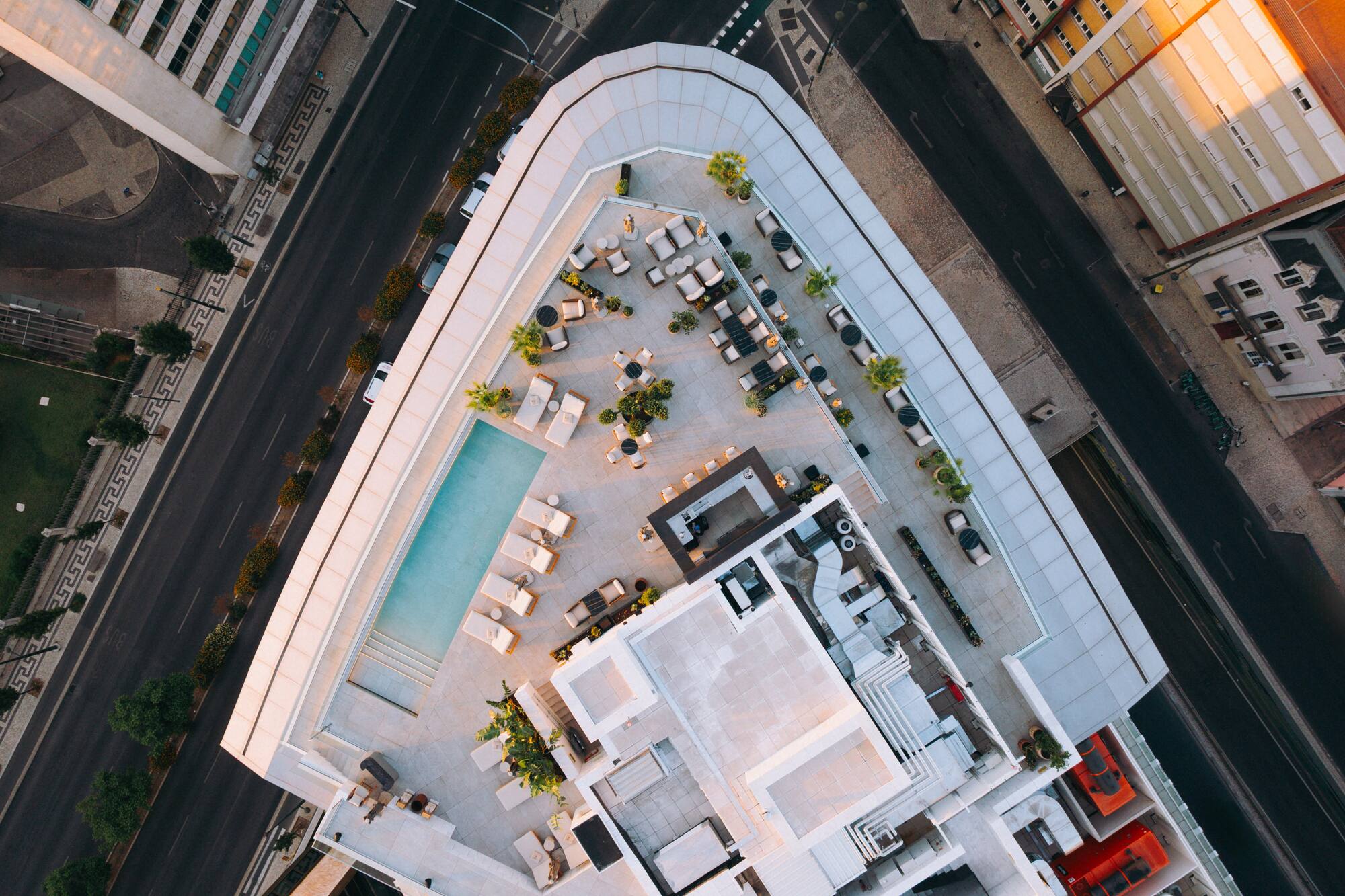 Aerial view of modern city rooftop terrace with pool and lounge areas.